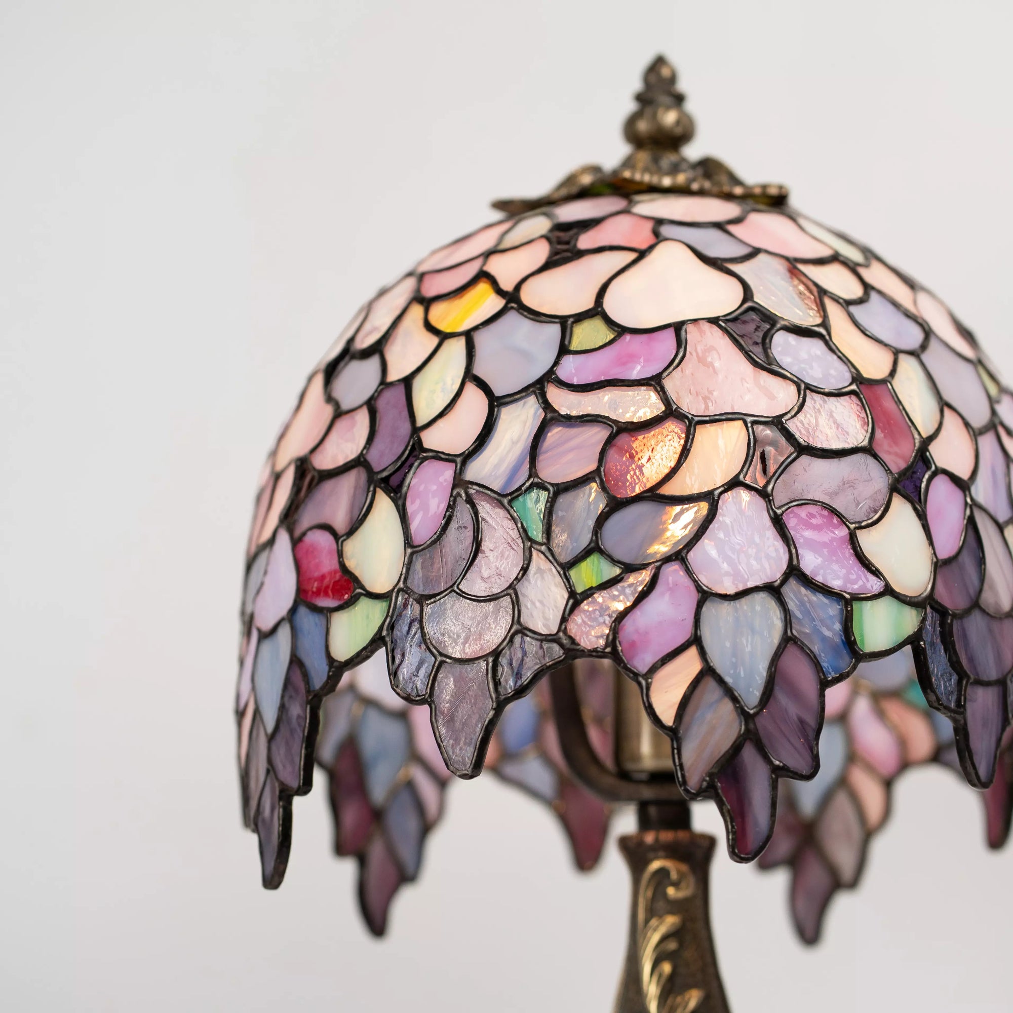 Close-up view of multicolored pastel Wisteria stained glass lampshade on a white background
