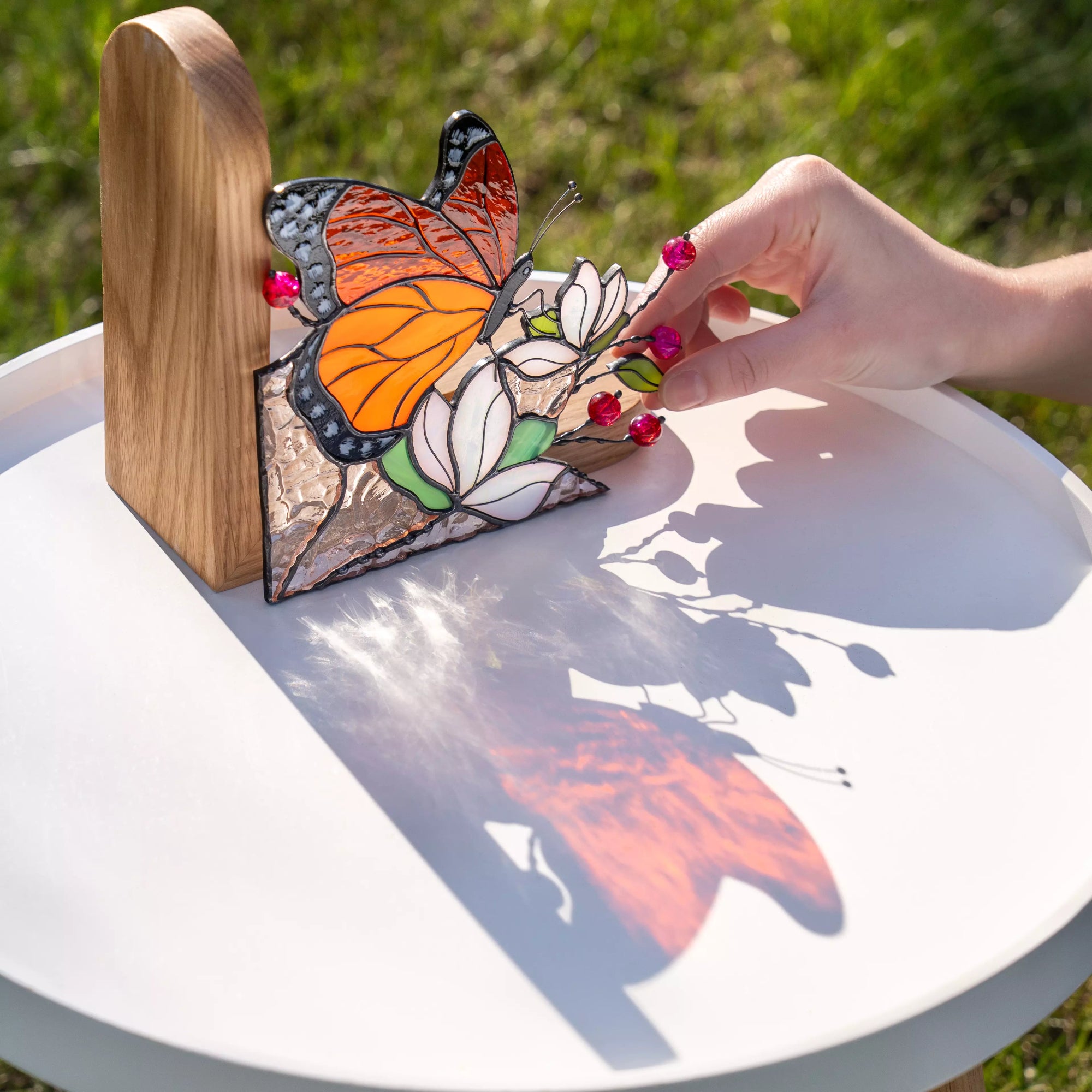 Orange stained glass butterfly bookend with black outlines, floral glass elements, and solid wooden stand.
