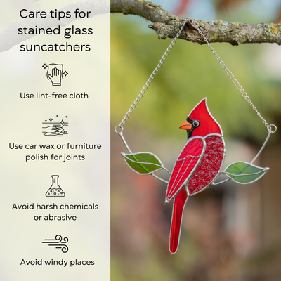 Cardinal suncatcher in sunlight hanging on a tree, shown with care instructions: use lint-free cloth, avoid chemicals and windy places