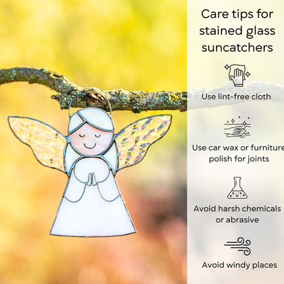 Stained glass angel with glistening wings hanging from a tree branch, lit by warm sunlight, with care instruction beside: use lint-free cloth, polish joints with car wax or furniture polish, avoid harsh chemicals, and windy places.