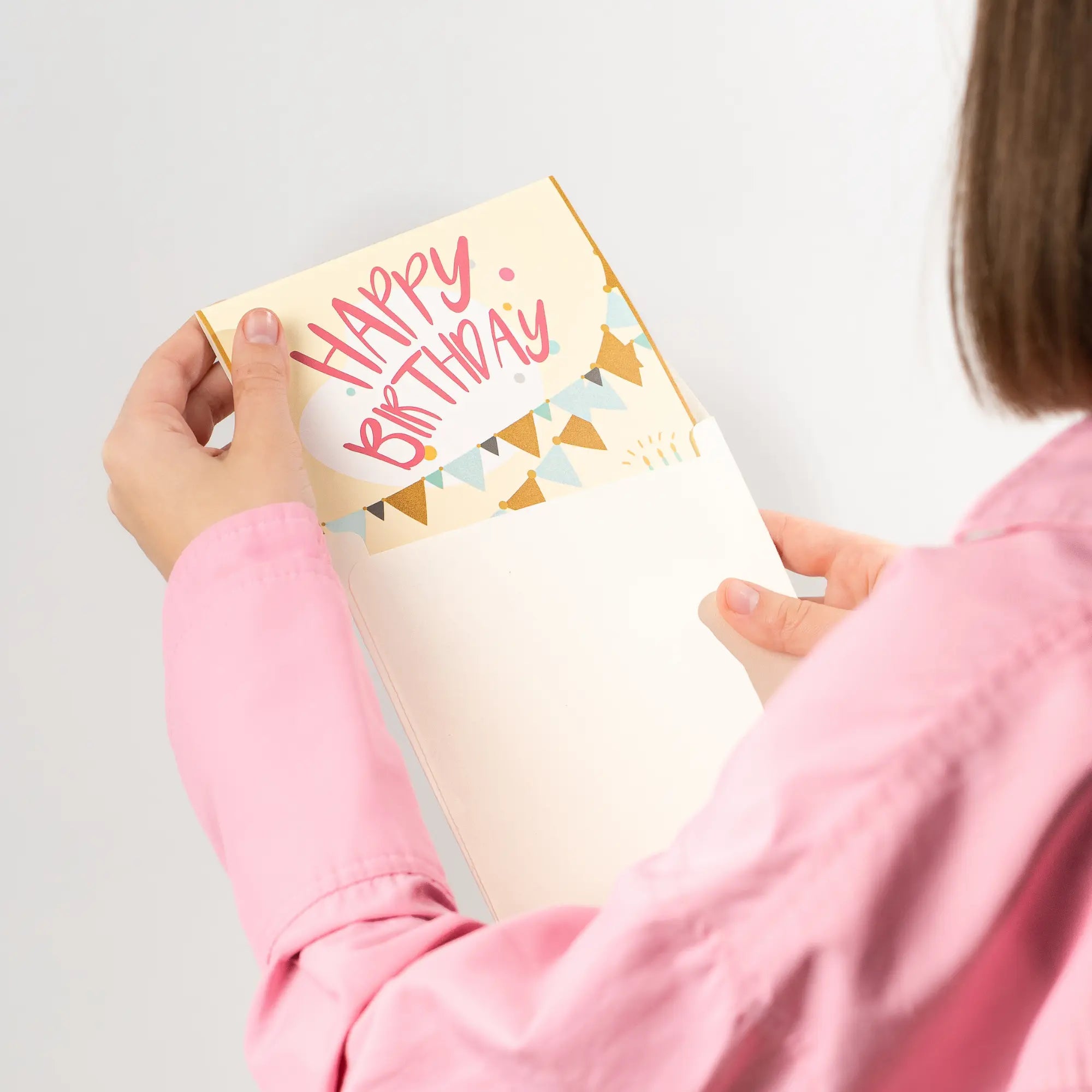Women holding a birthday card with 'Happy Birthday' text on a plain background