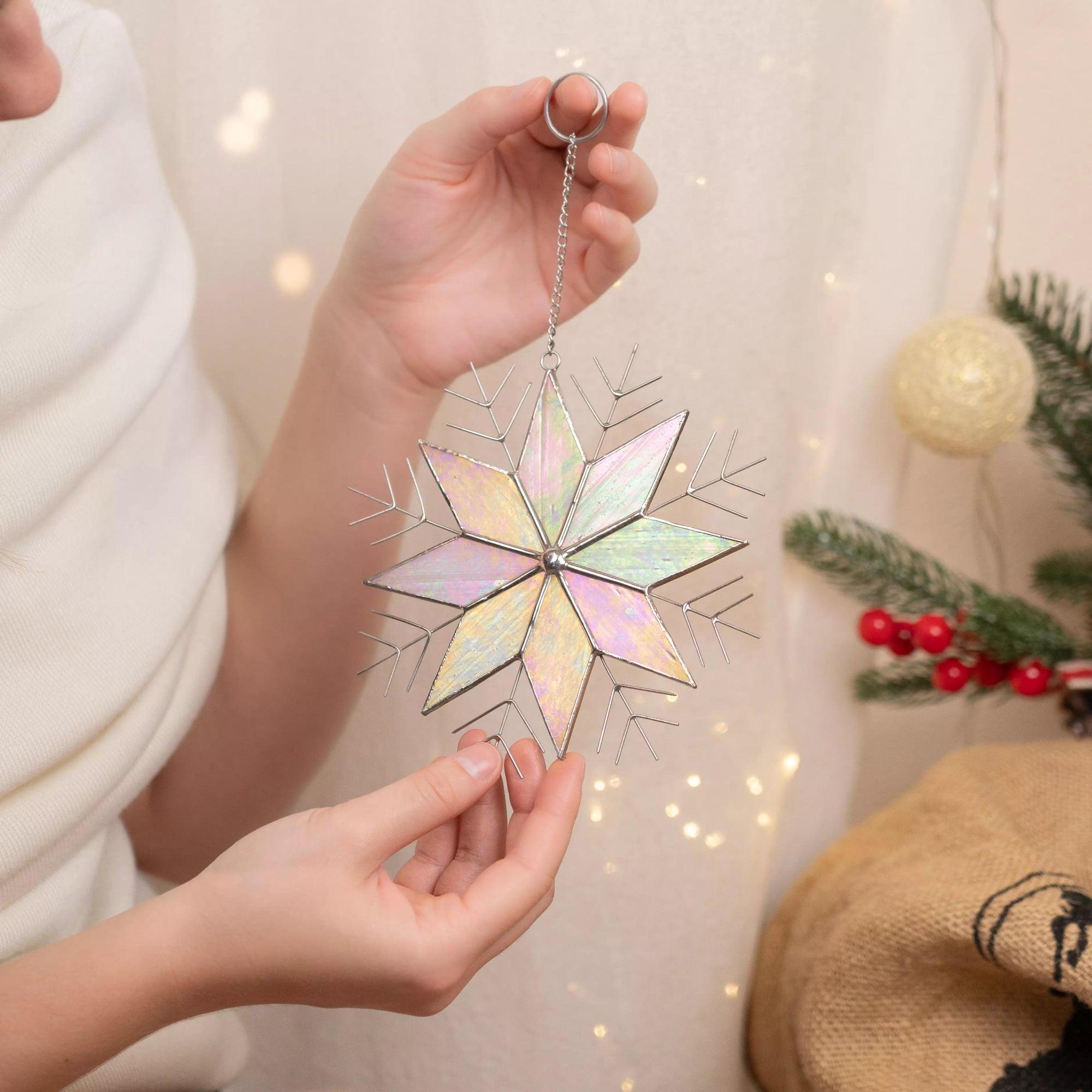 Hands  holding a decorative Christmas snowflake ornament with a blurred festive background