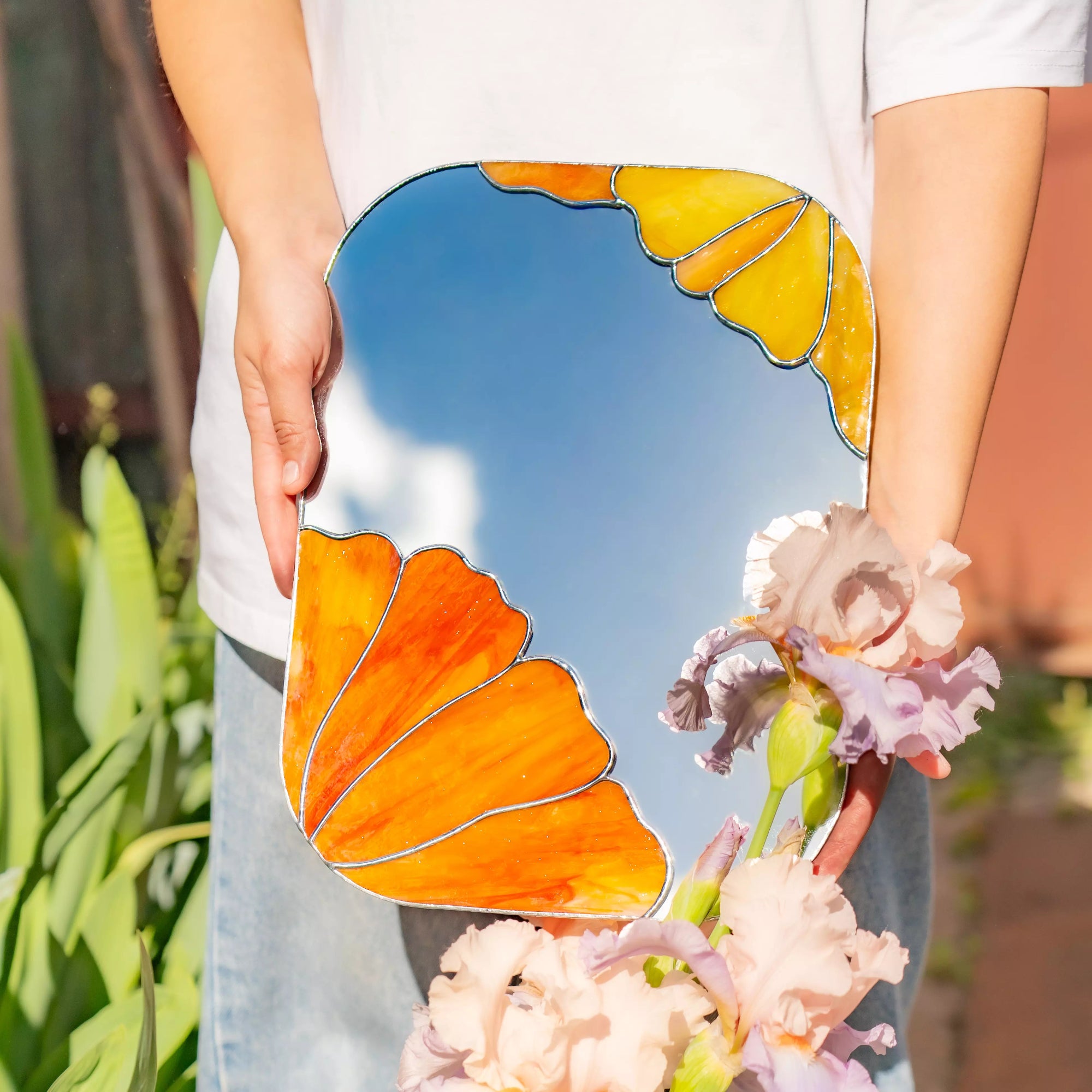 Person holding a floral mirror with floral design outdoors