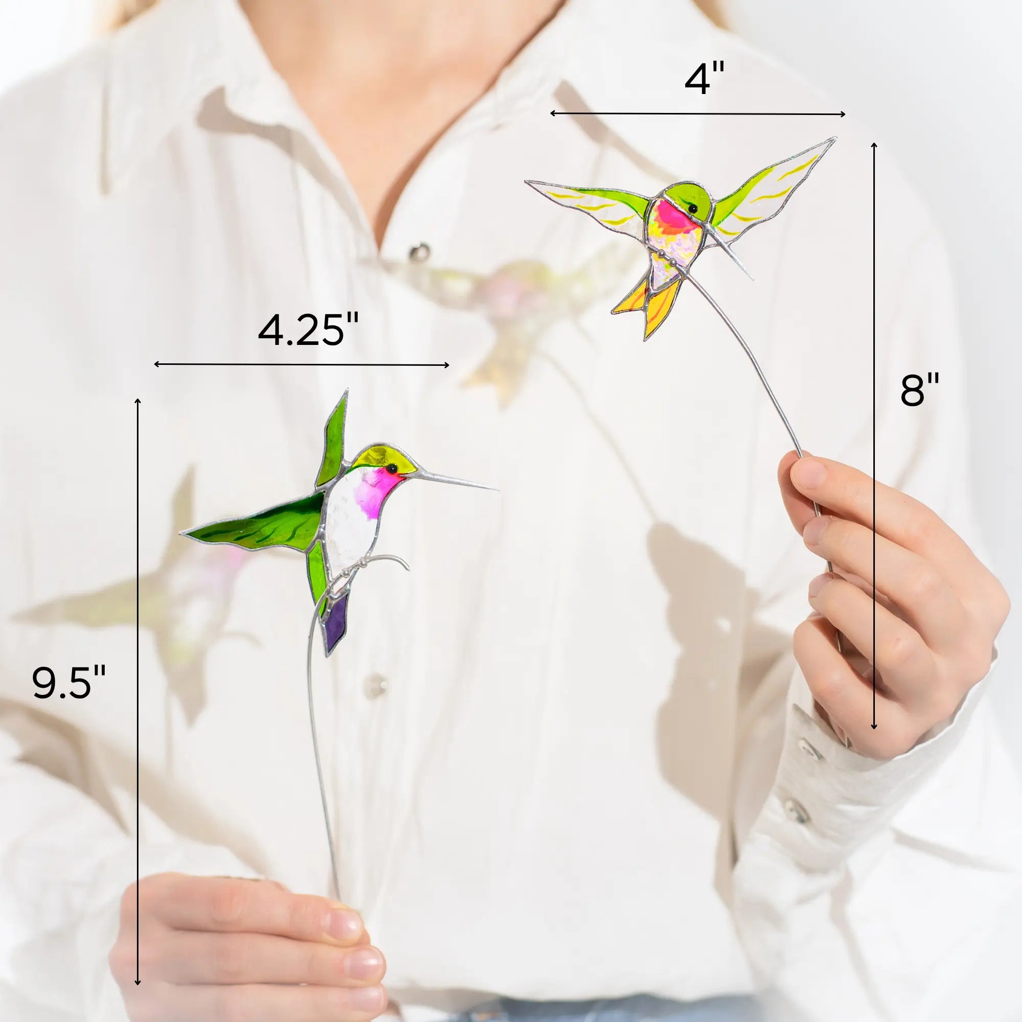 Person holding a stained glass hummingbird plant stakes with measurements indicated
