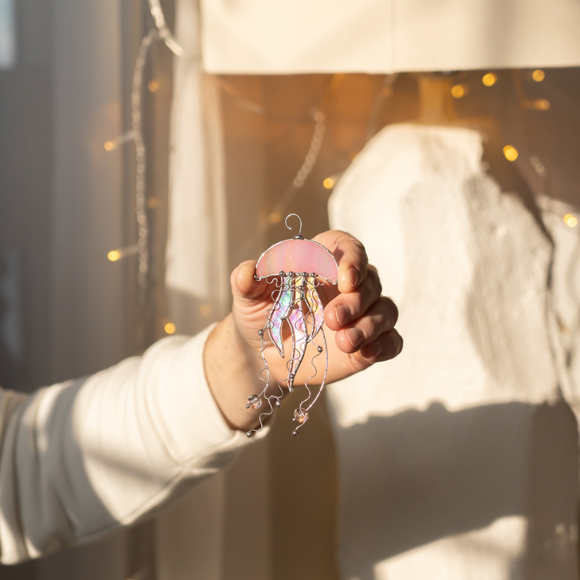 Hand holding a stained glass suncatcher pink jellyfish window hanging