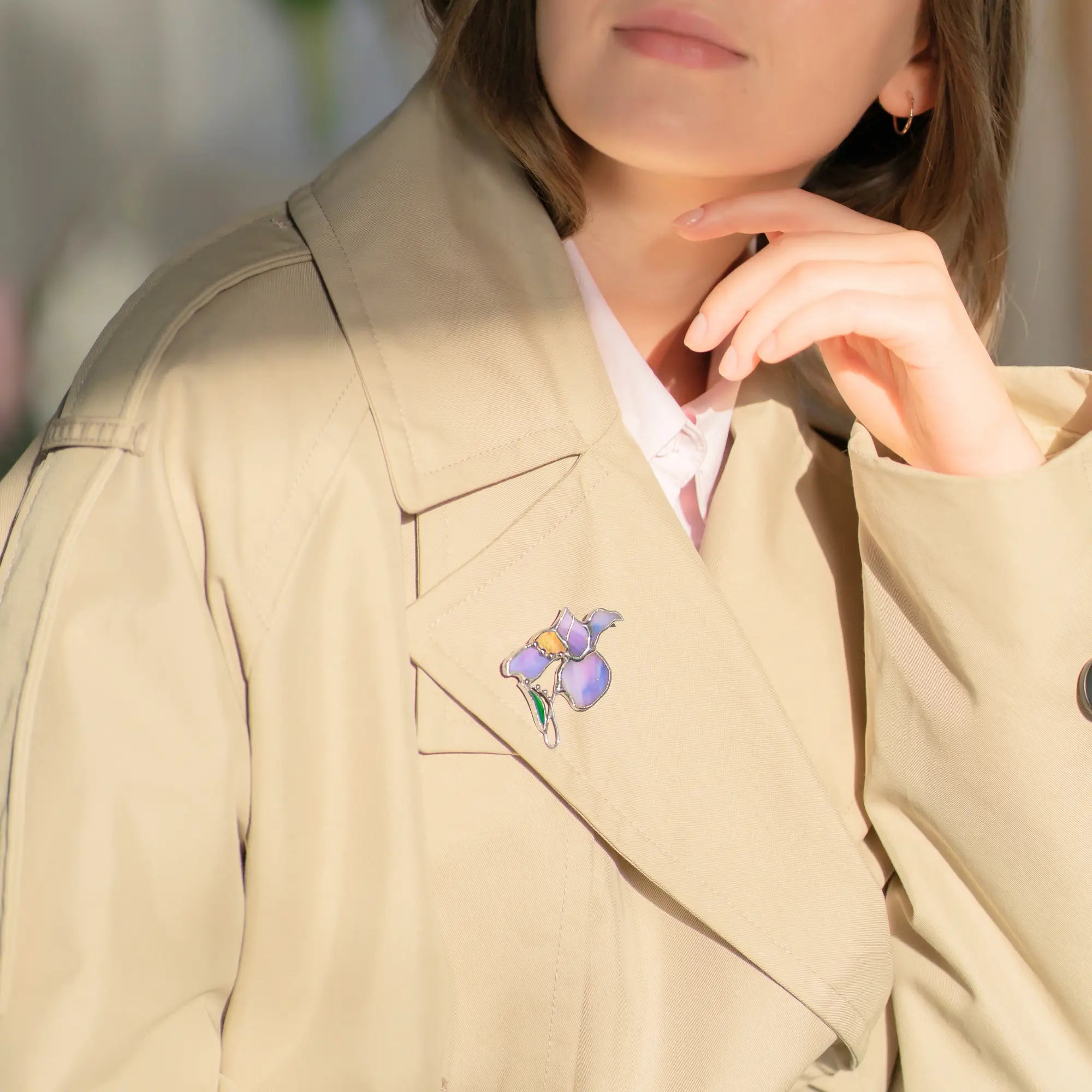Women wearing a beige coat with a floral iris brooch on a blurred background