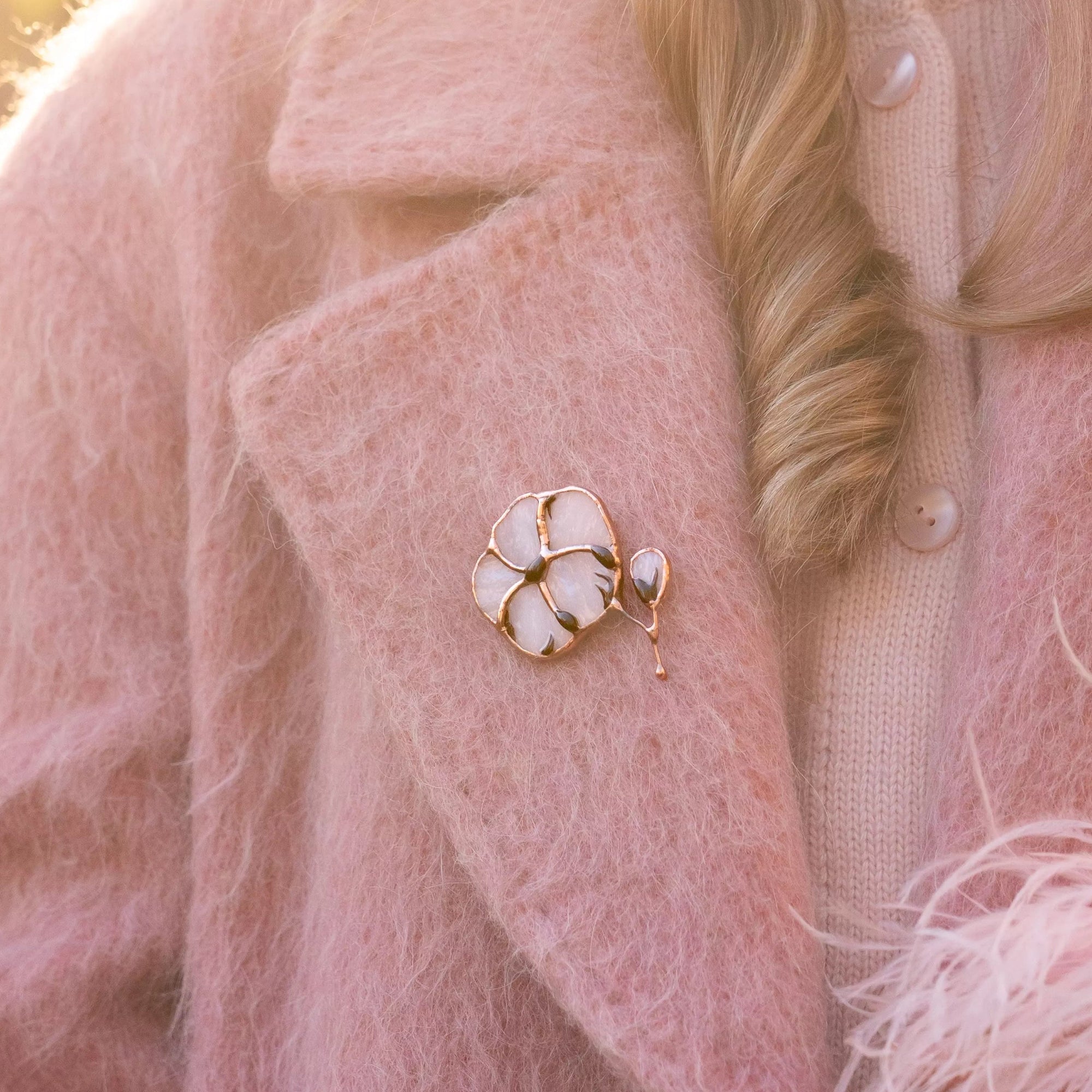 Person wearing a pink coat with a stained glass cotton brooch