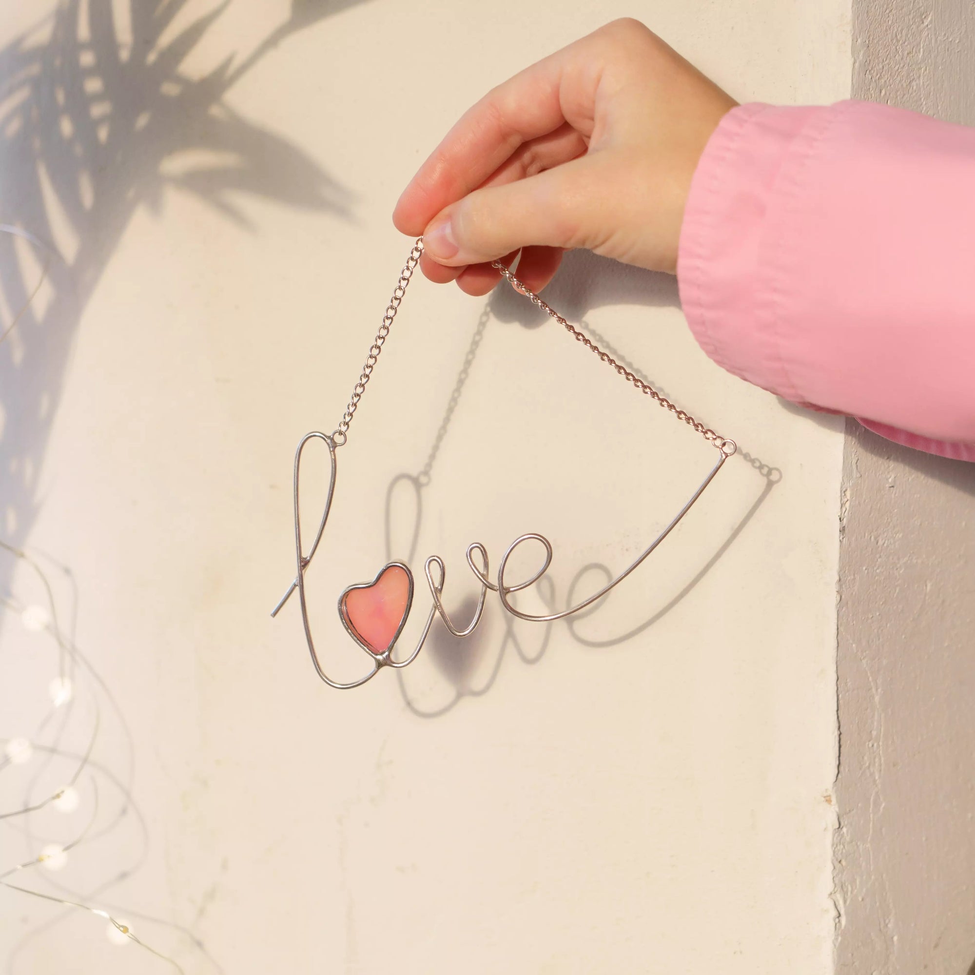 Love stained glass wire sign displayed against a red background, featuring a glowing pink iridescent heart.