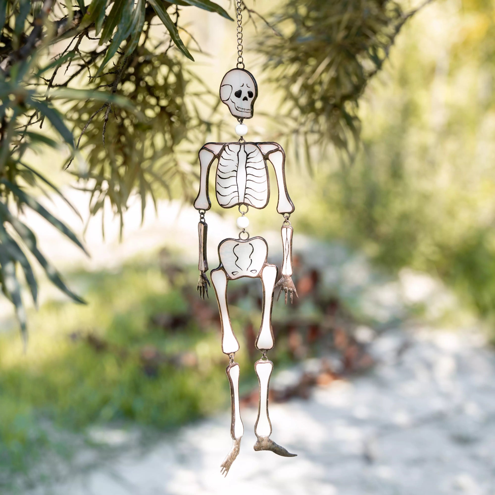 Skeleton Halloween suncatcher outside among tree branches