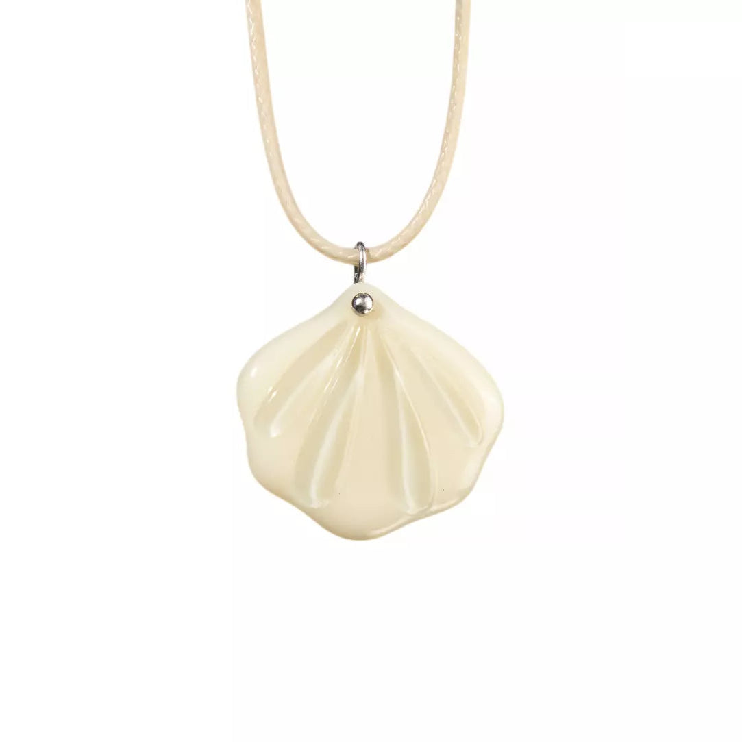 Shell-shaped pendant on a necklace against a white background