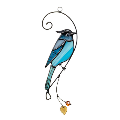 Stained glass Steller’s jay suncatcher with curved branch, amber bead, and leaf, shown against a white wall background