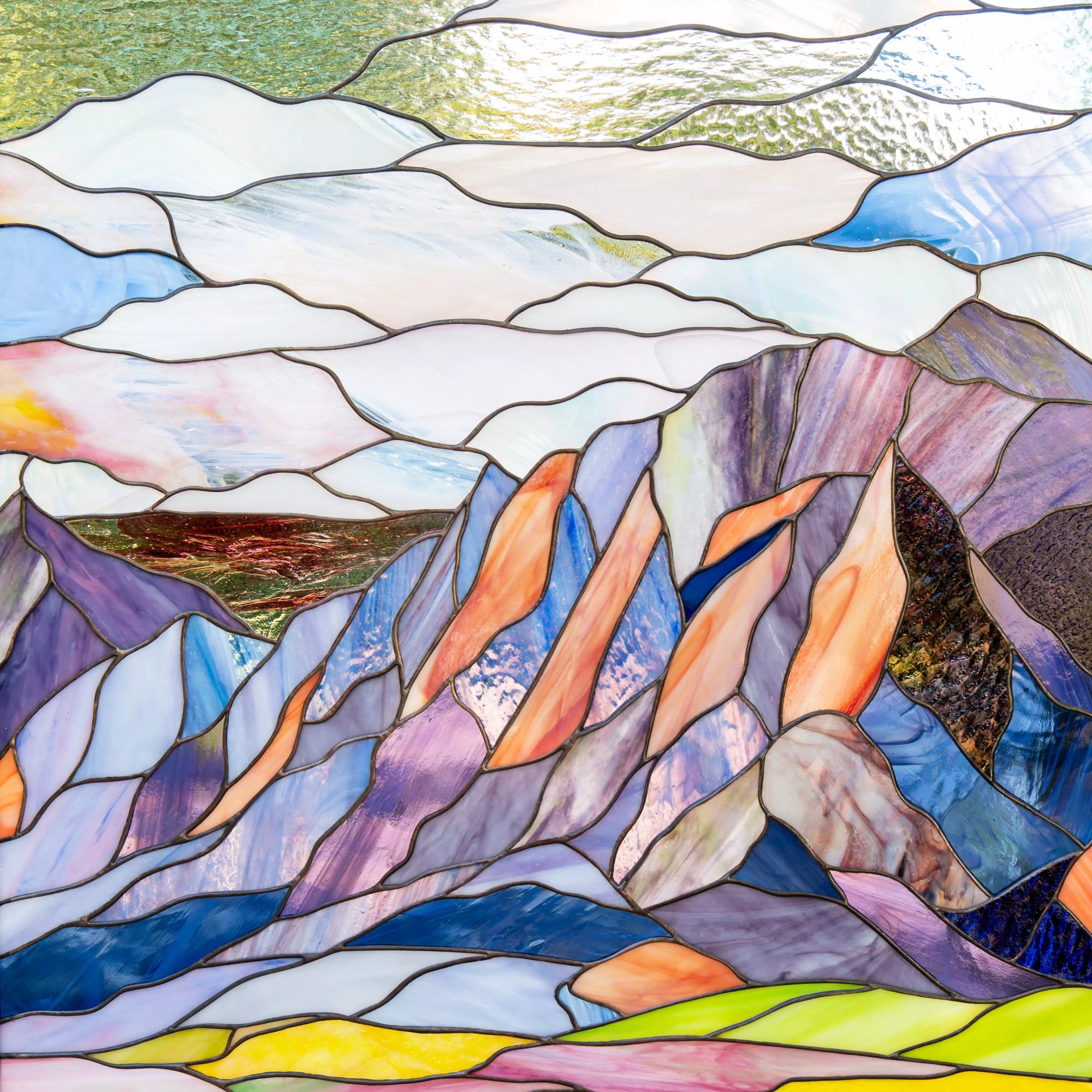 Custom stained glass panel of a mountain landscape with colorful glass pieces.