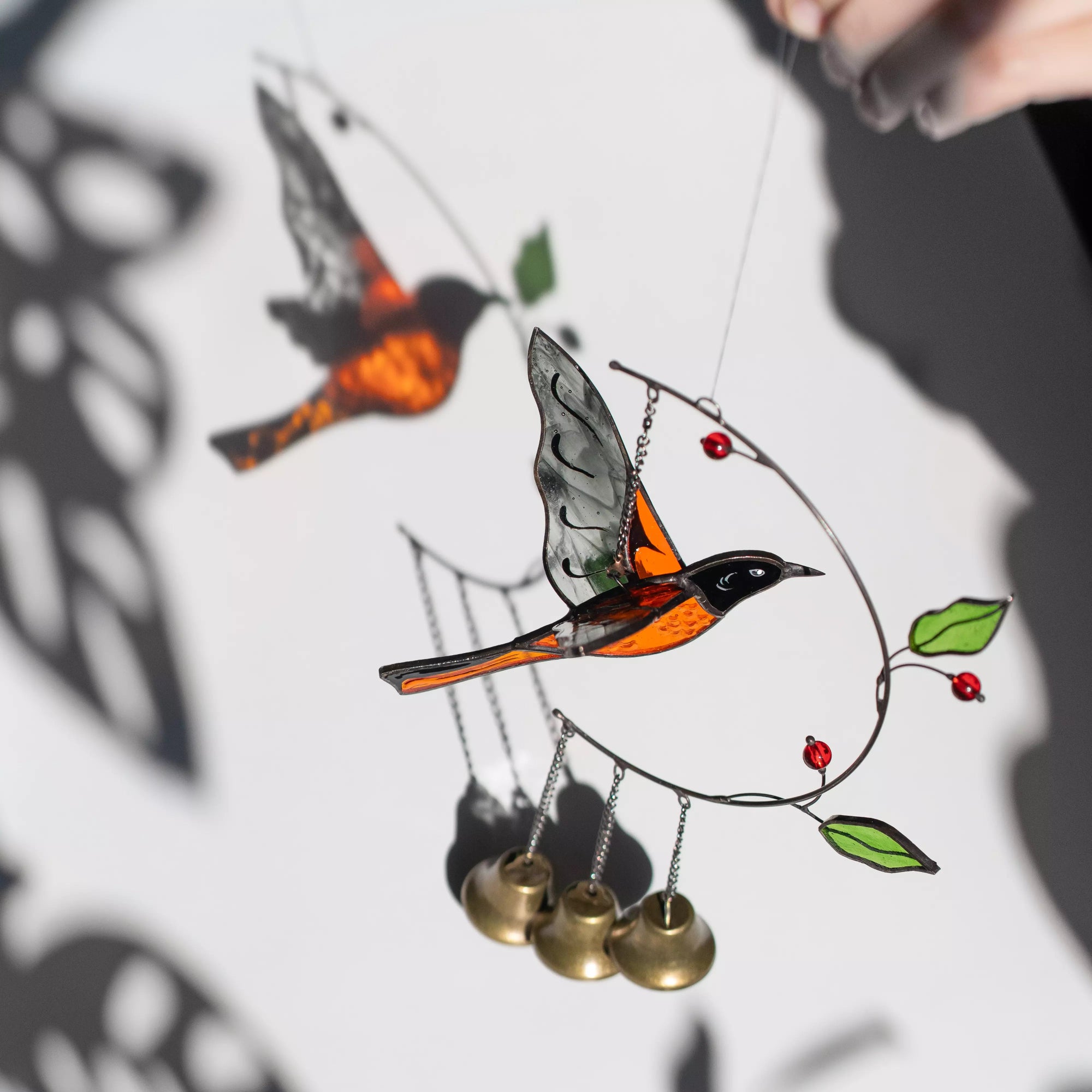 Stained glass baltimore oriole ornament with bells on a white background
