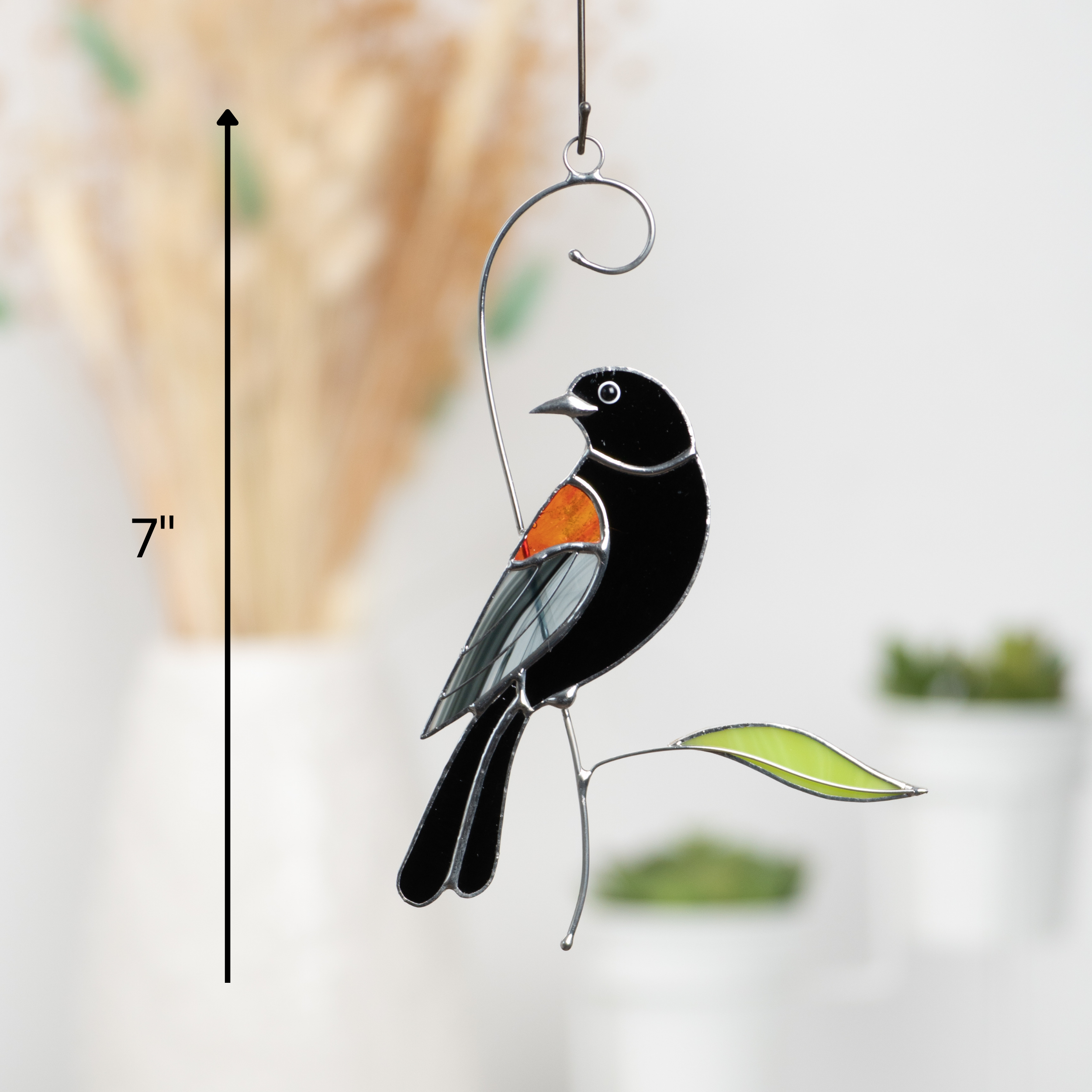 Elegant stained glass blackbird hanging indoors, showcasing its size as 7 inches and vibrant orange wing.