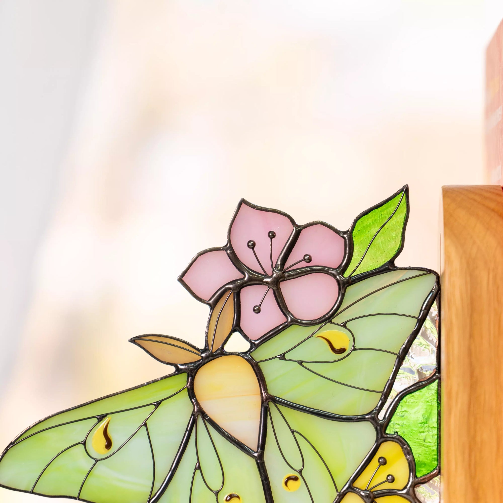 Close-up of stained glass butterfly bookend showing green wings and pink flower details with solder lines
