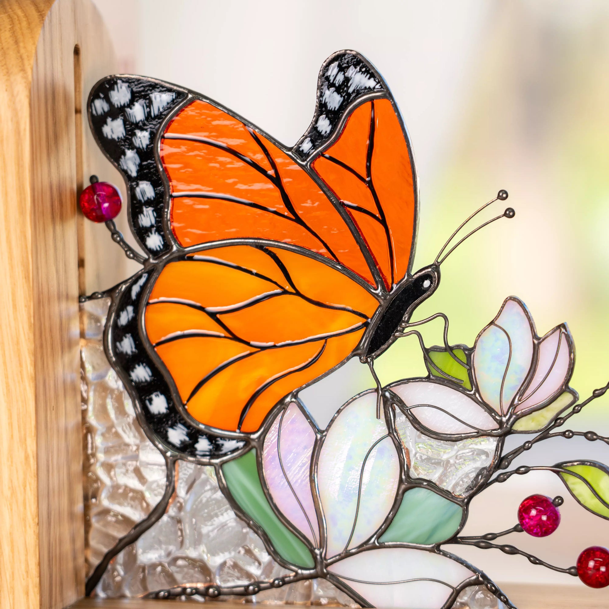 Stained glass butterfly bookend featuring bright orange wings, glass flowers, and a wooden base.