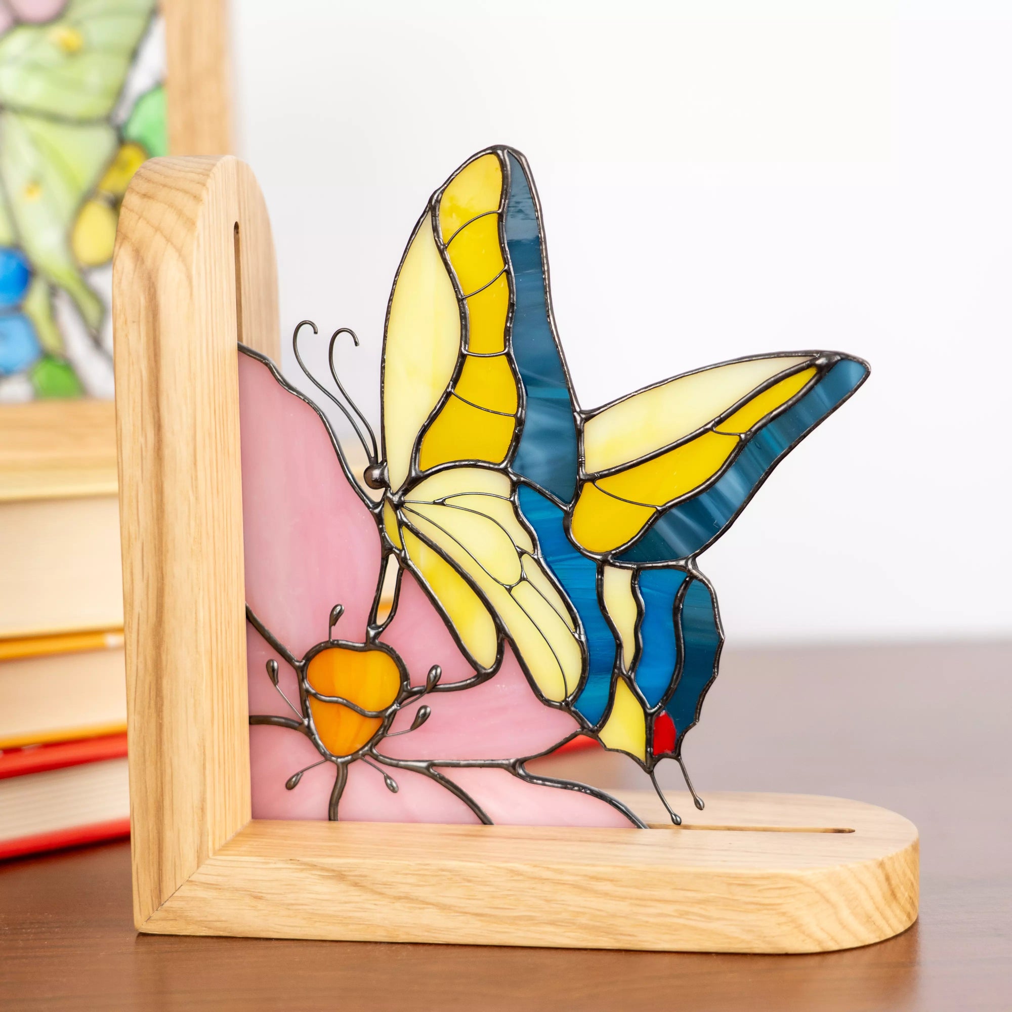 Stained glass yellow butterfly bookend panel in a wooden frame on a table.