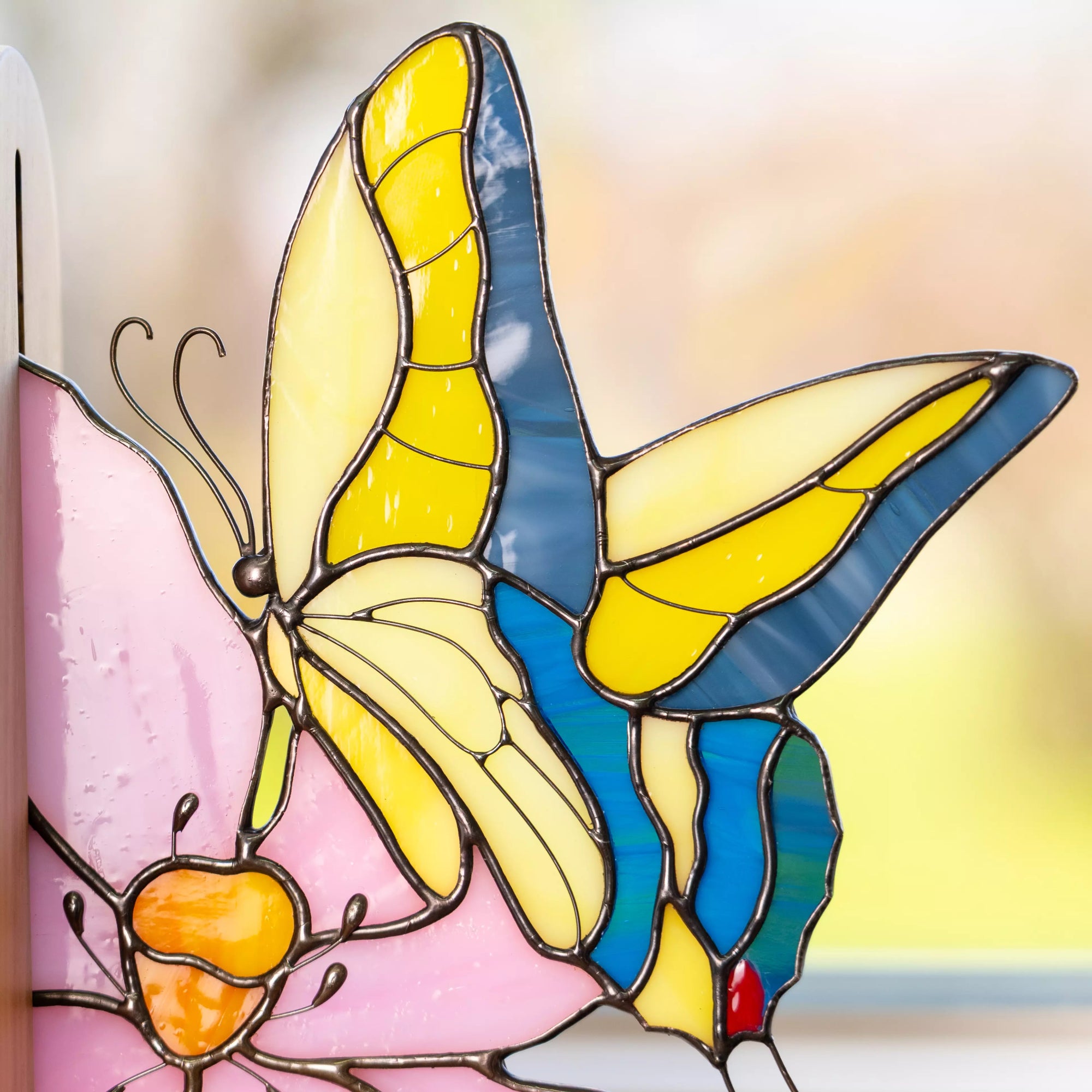 Close-up of stained glass butterfly wings made of yellow and blue glass pieces with soldered lines