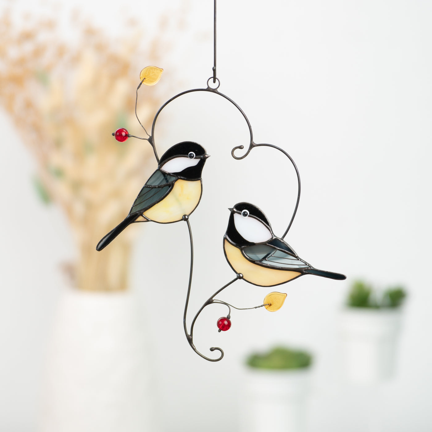 Two stained glass chickadees with yellow bellies and black caps, perched on a metal branch with red and yellow beads.