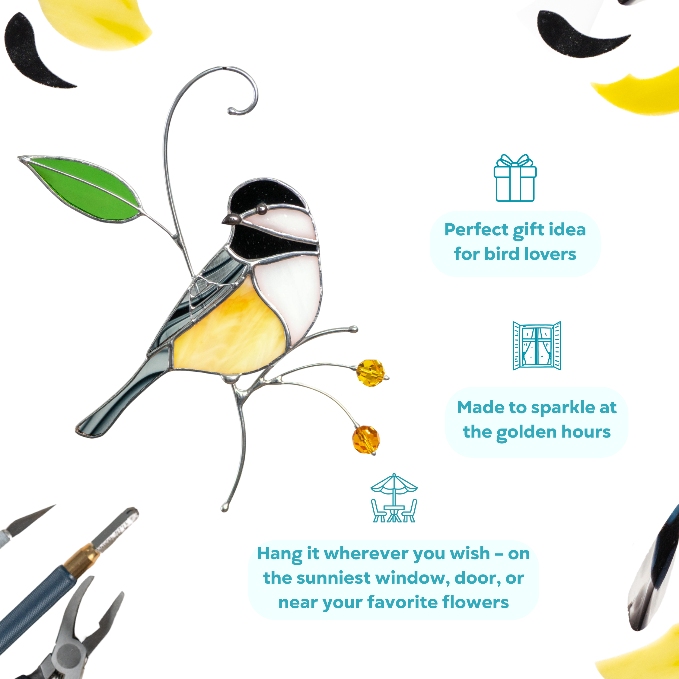 Chickadee suncatcher with yellow body, black and white head, amber beads and green leaf, hanging near tools on white background.