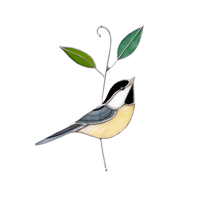 Yellow and black stained glass chickadee with two green leaves, hanging in soft natural light with floral background