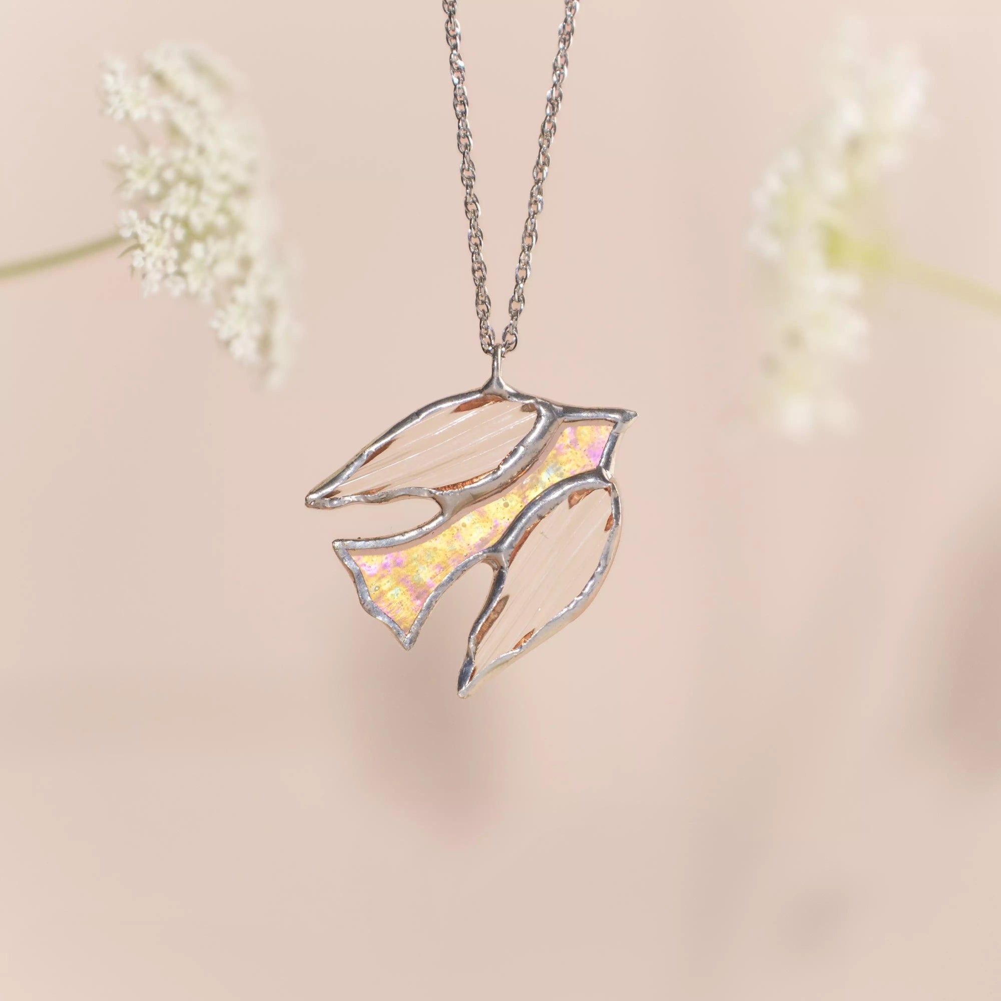 Stained glass clear bird pendant necklace on a soft pink background
