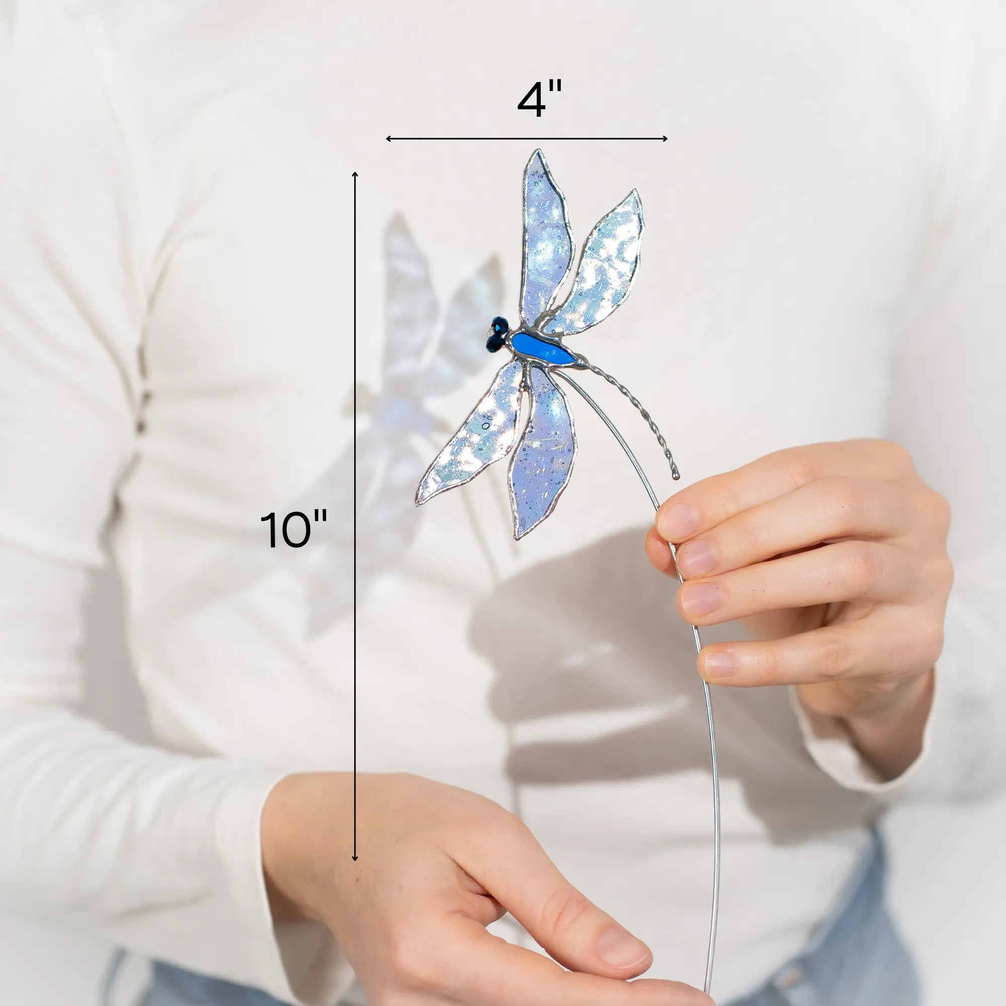 Stained glass dragonfly held by a person with measurements indicated 4 x 10 inches