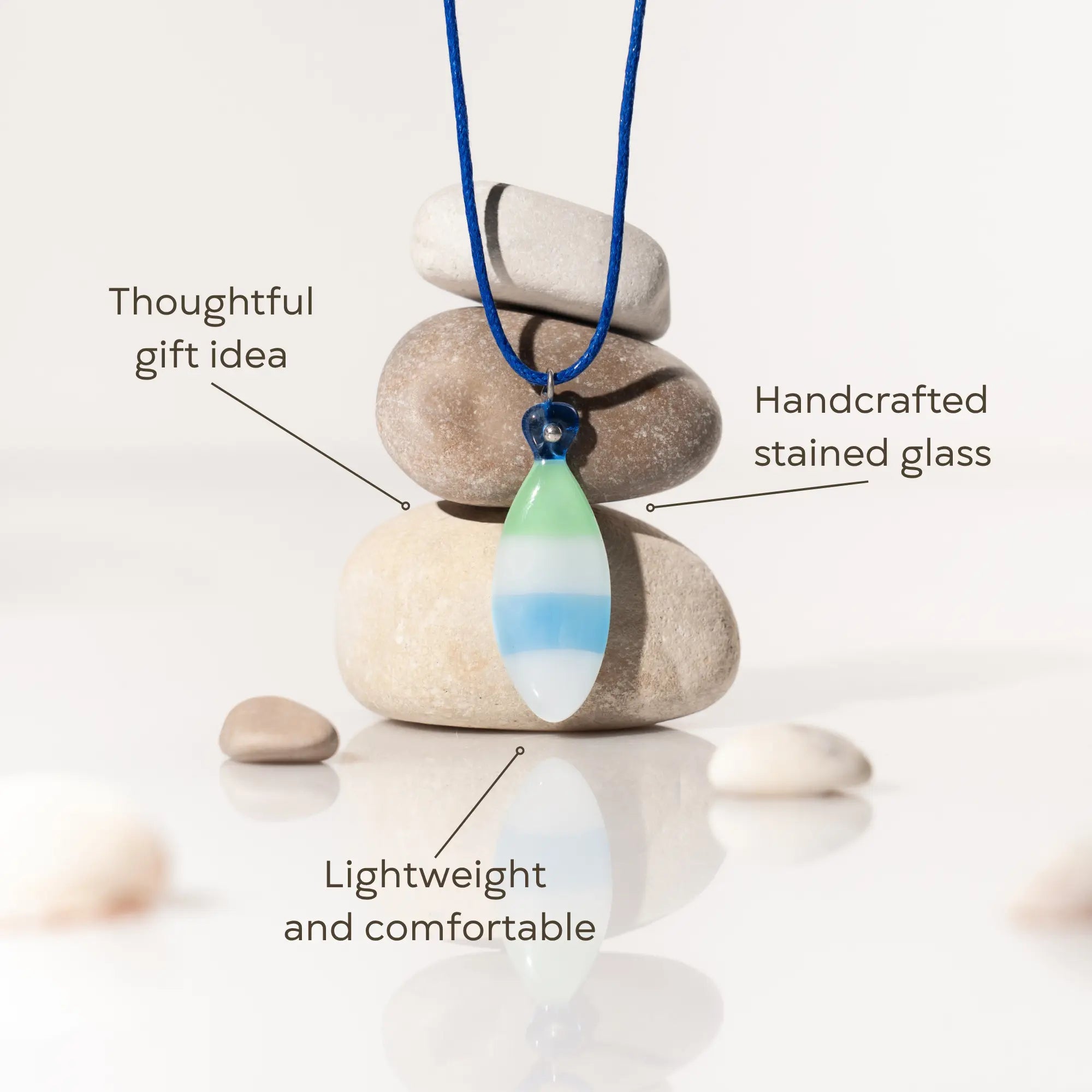 Necklace with a handcrafted stained glass pendant on stones, labeled as a thoughtful gift idea.