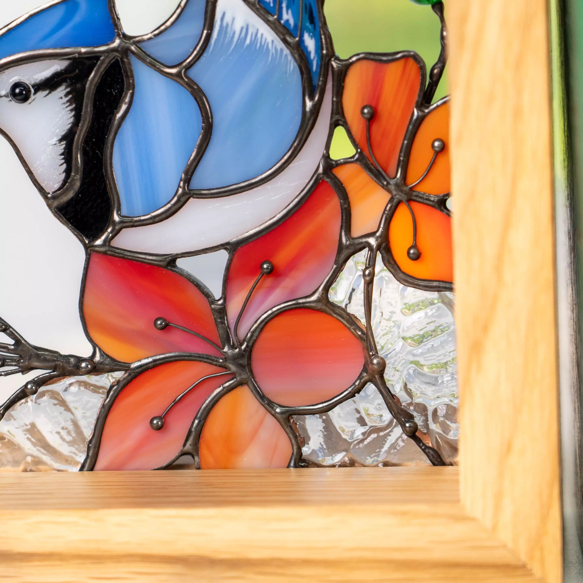 Macro view of orange stained glass flowers beneath the blue jay.