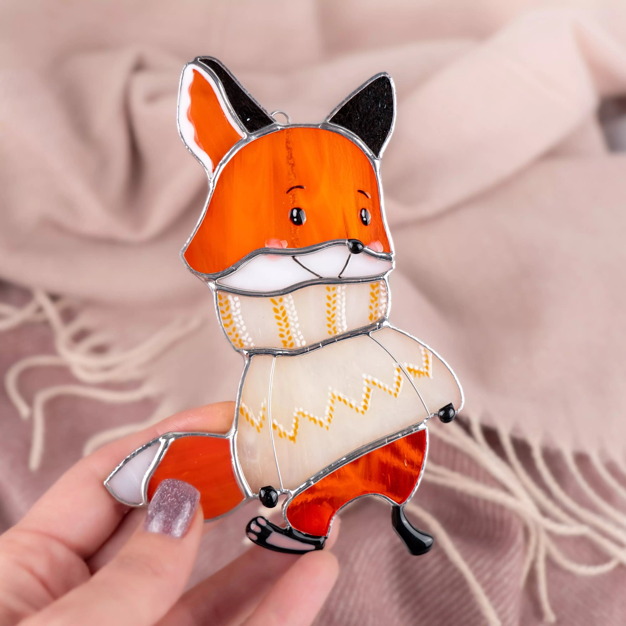 Stained glass suncatcher featuring fox held by a hand against a soft pink background