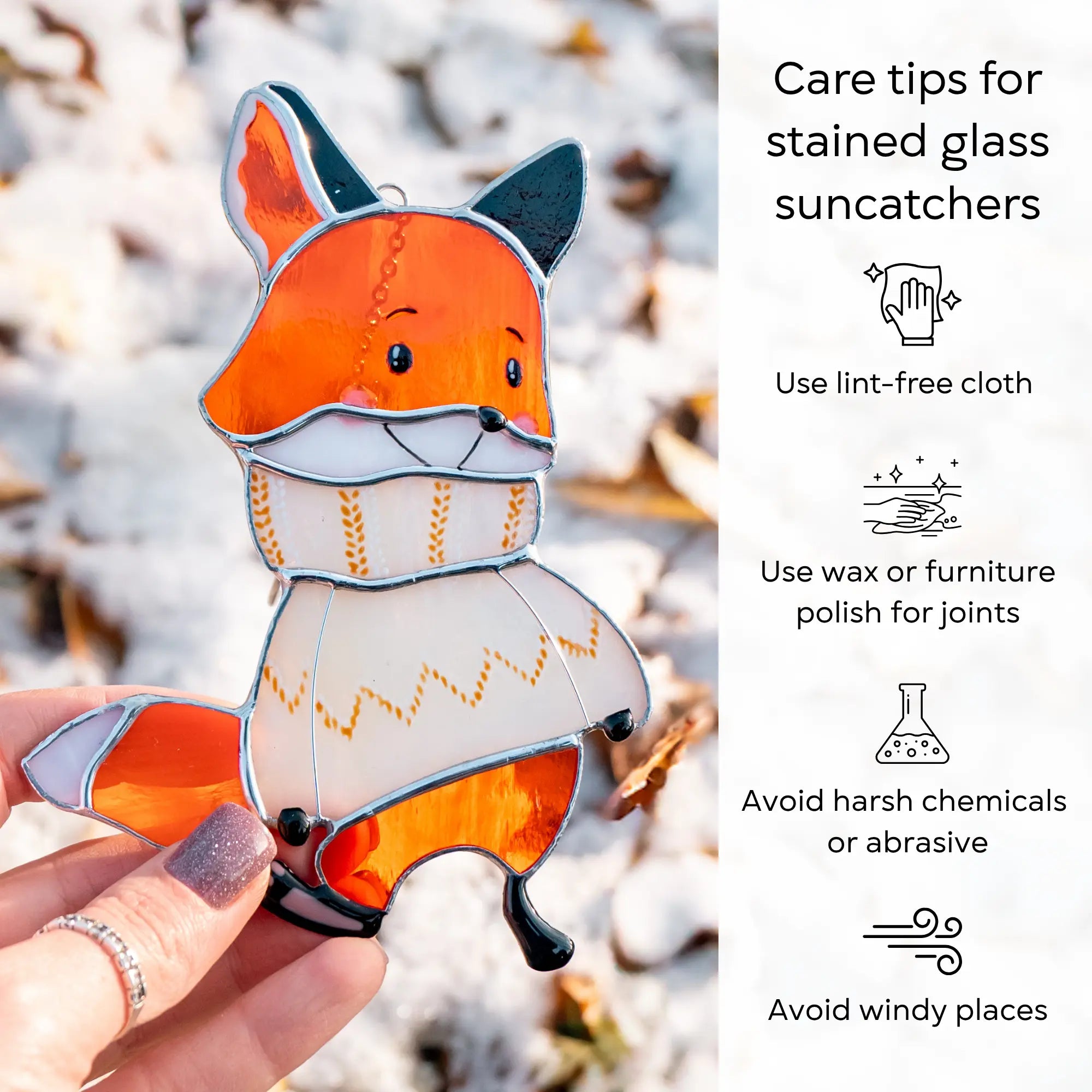 Stained glass suncatcher fox  in a sweater held by a hand with care tips on a snowy background: use lint-free cloth, polish joints with car wax or furniture polish, avoid harsh chemicals, and windy places.