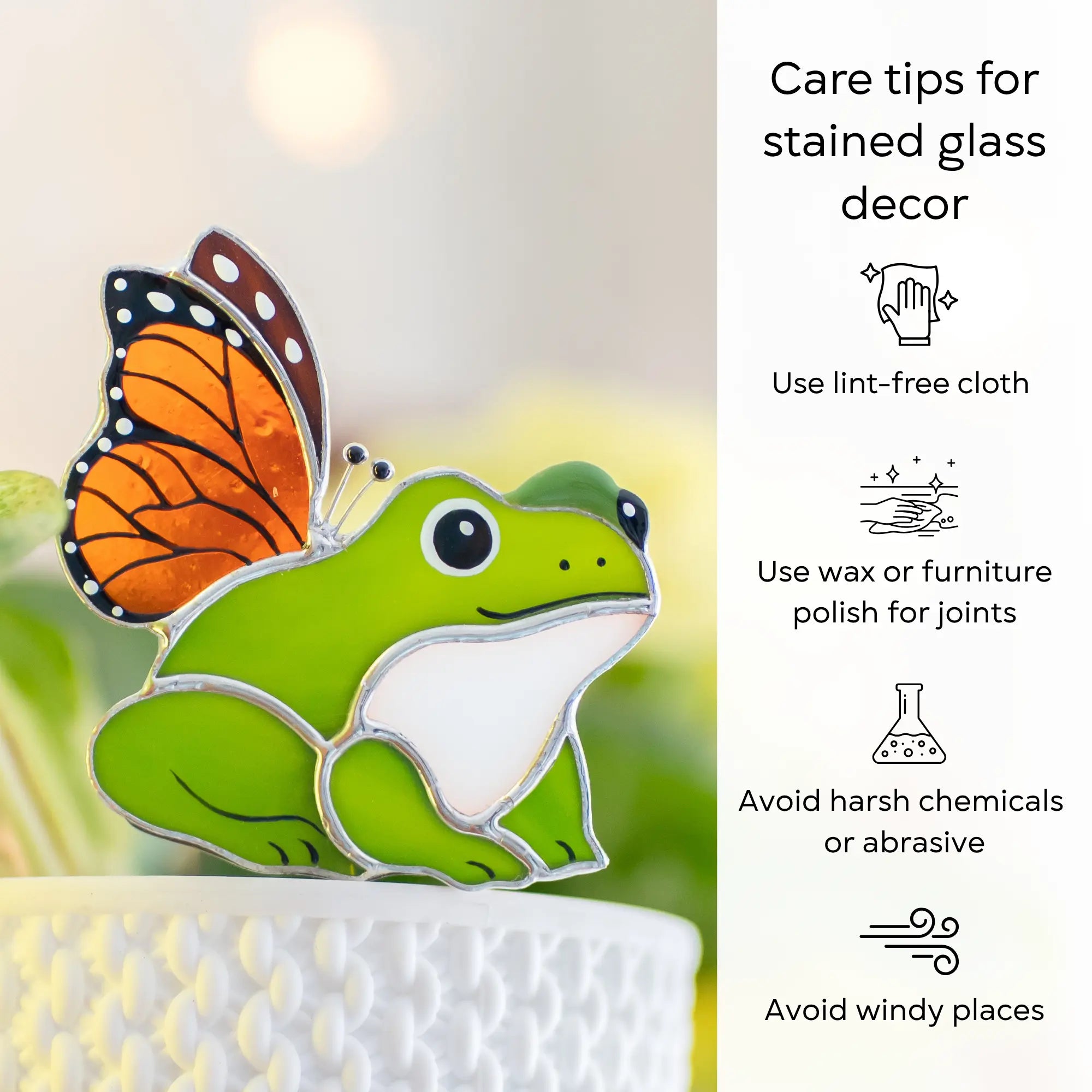 Stained glass frog with butterfly wings on a white stand, with care tips on the right: use lint-free cloth, polish joints with car wax or furniture polish, avoid harsh chemicals, and windy places.