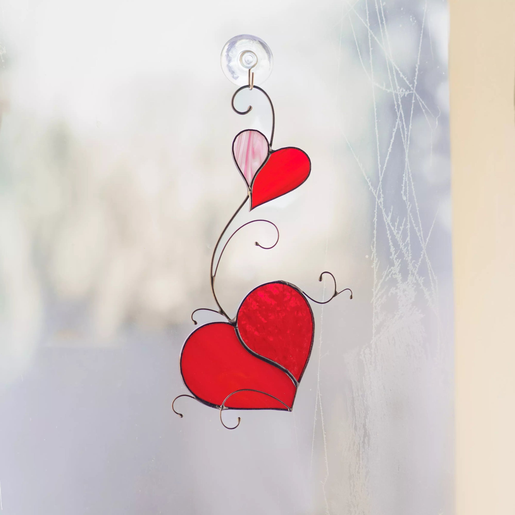 Stained glass two hearts suncatcher hanging on a window with a suction cup