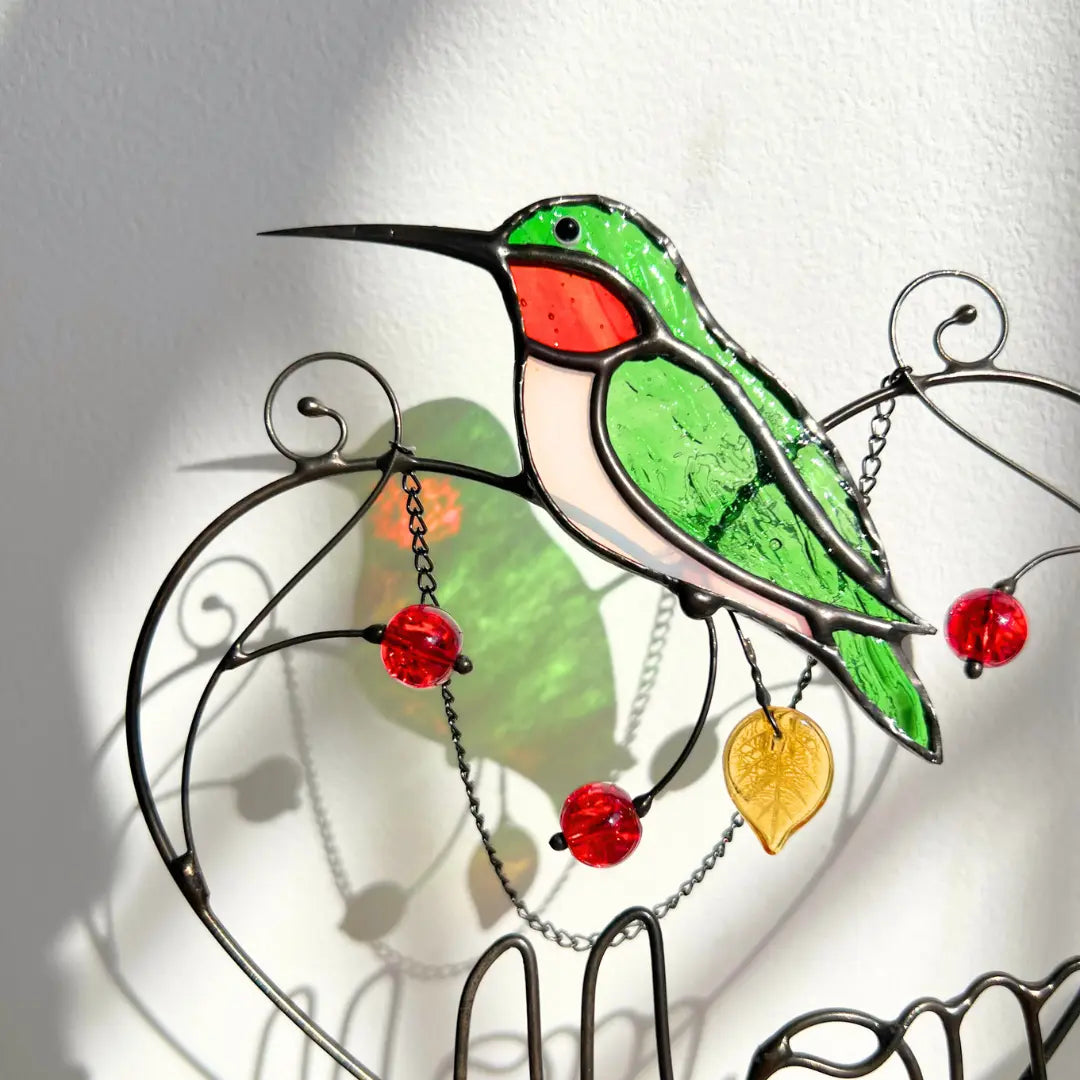 Close-up of stained glass hummingbird with red accents on a white background
