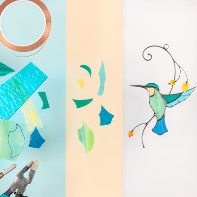 A stained glass hummingbird on the right, surrounded by cut glass pieces, copper foil, and tools on a pastel background

