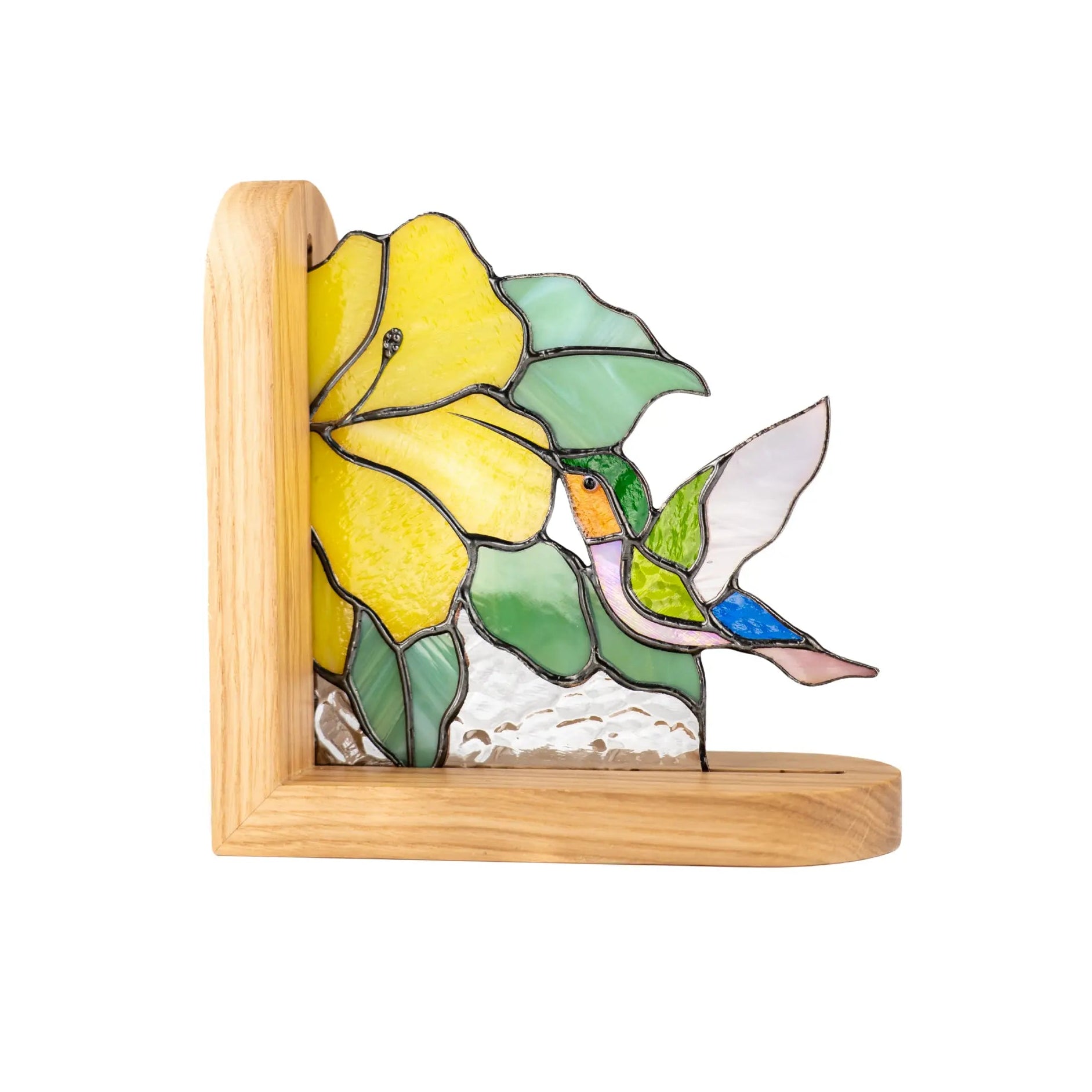Stained glass hummingbird flying toward a yellow flower, set in a wooden bookend with textured clear glass base.