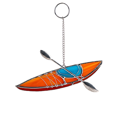A stained glass suncatcher shaped like an orange kayak with a blue seat and crossed paddles, hanging on a chain.