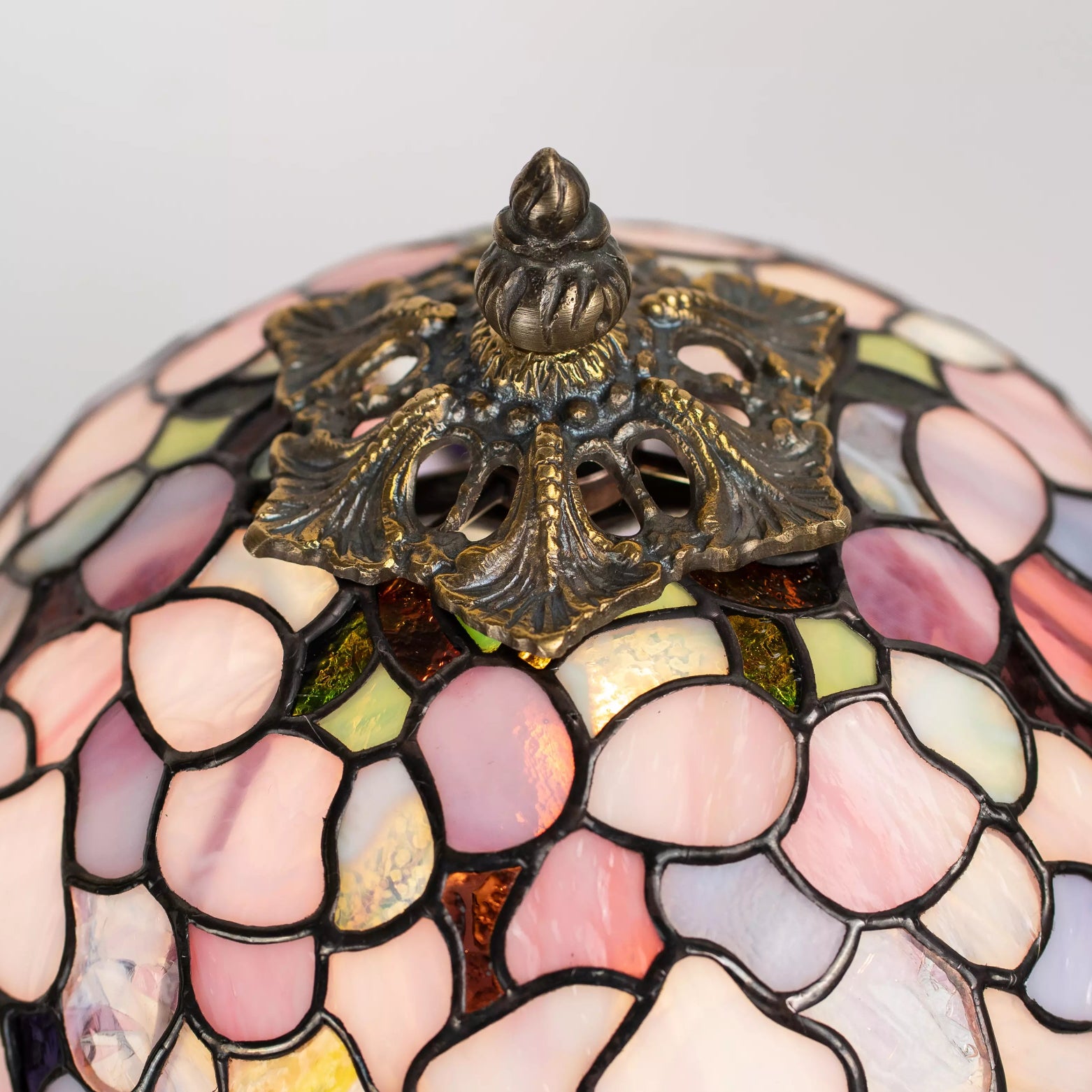 Stained glass Wisteria lamp with floral pattern and decorative finial on a light gray background