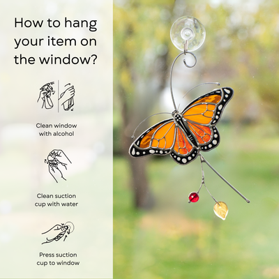 Monarch butterfly suncatcher on a window, instructions for hanging visible on the left: clean window and suction cup, press a cup to the surface.