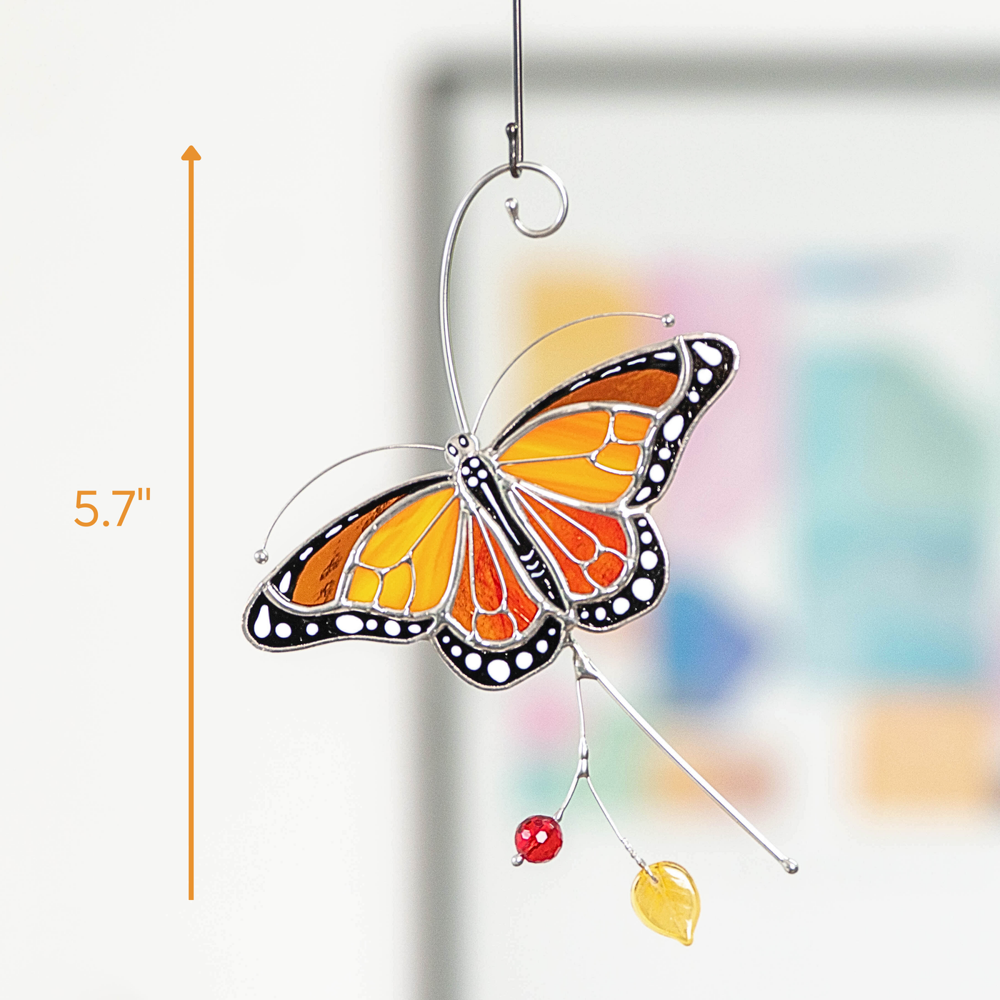 Hanging monarch butterfly suncatcher next to measurement scale indicating its size at 5.7 inches.