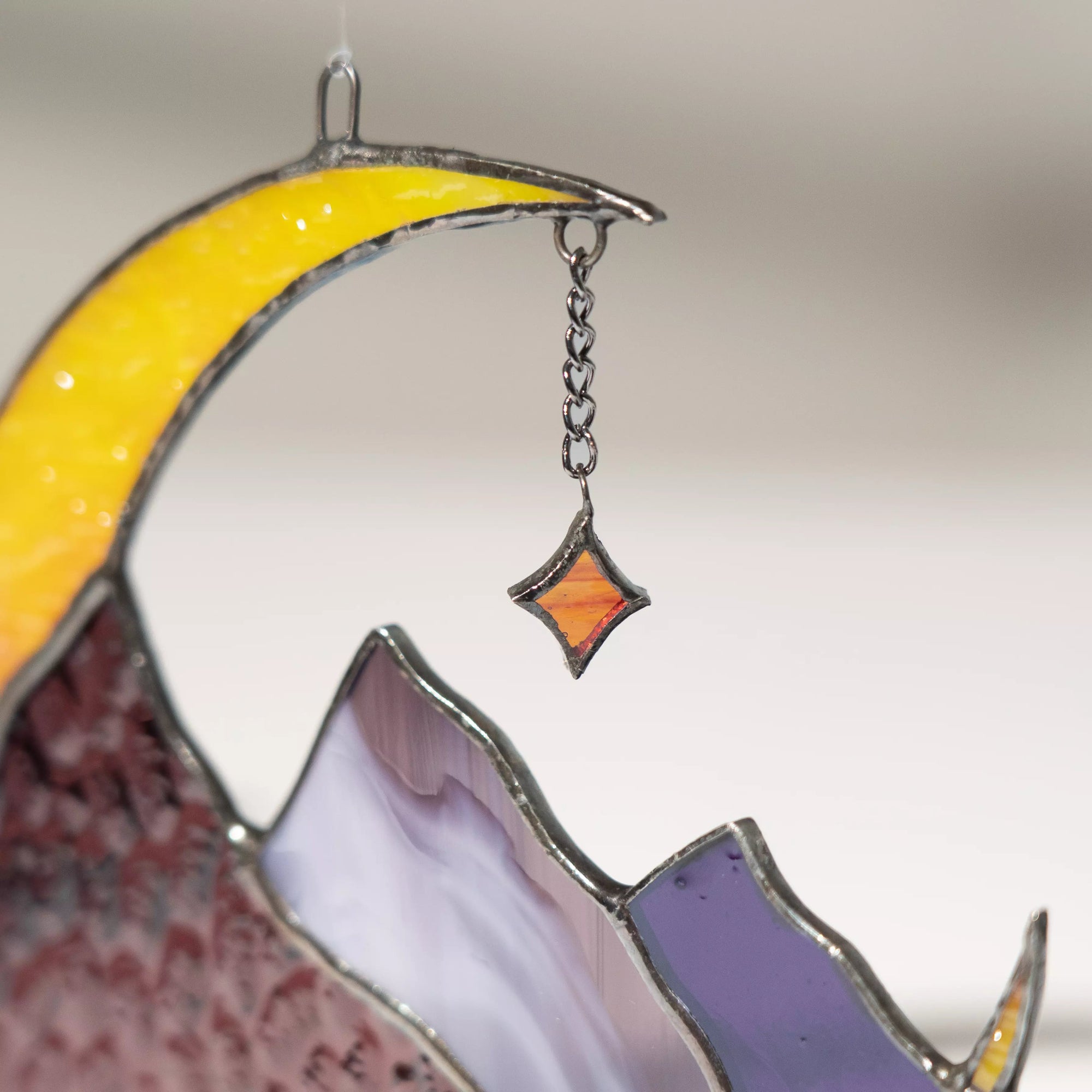 Close-up view of stained glass moon and star ornament with a blurred background