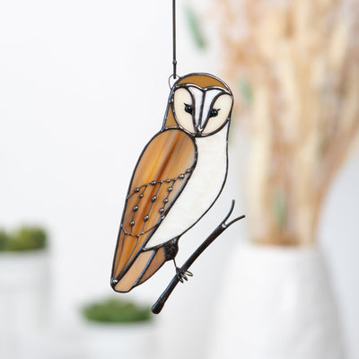 Hanging stained glass owl with warm amber and white tones, symbolizing wisdom and tranquility