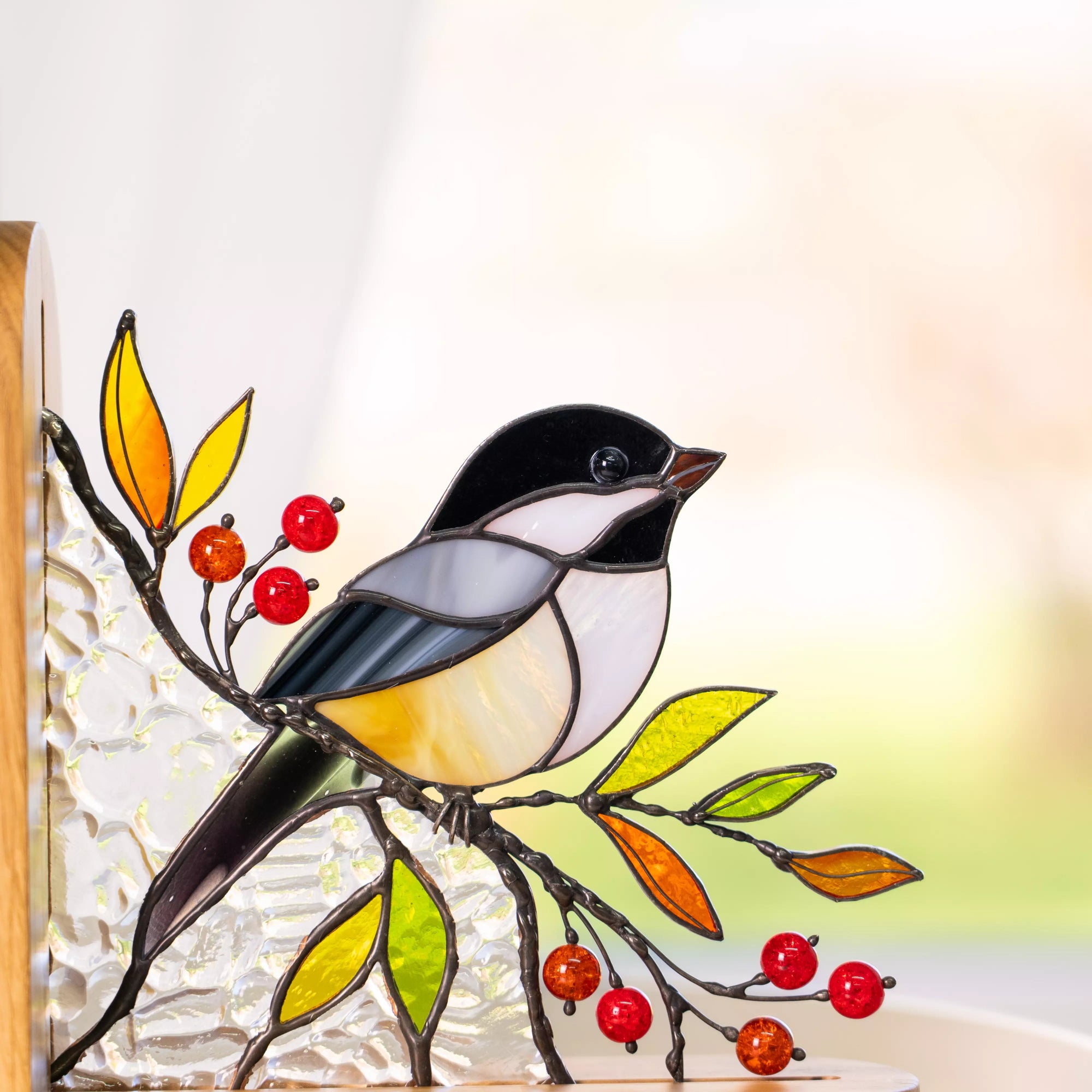 Stained glass chickadee bird perched on a branch with red berries and colorful leaves, set in a wooden bookend with textured clear glass.