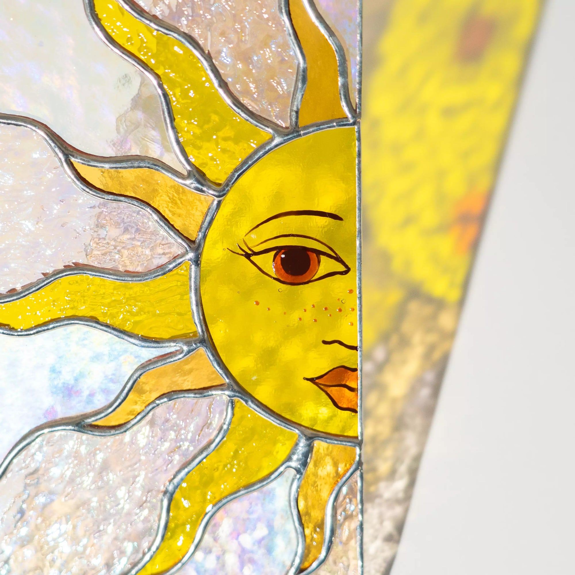 Stained glass panel featuring sun with a face on a white background