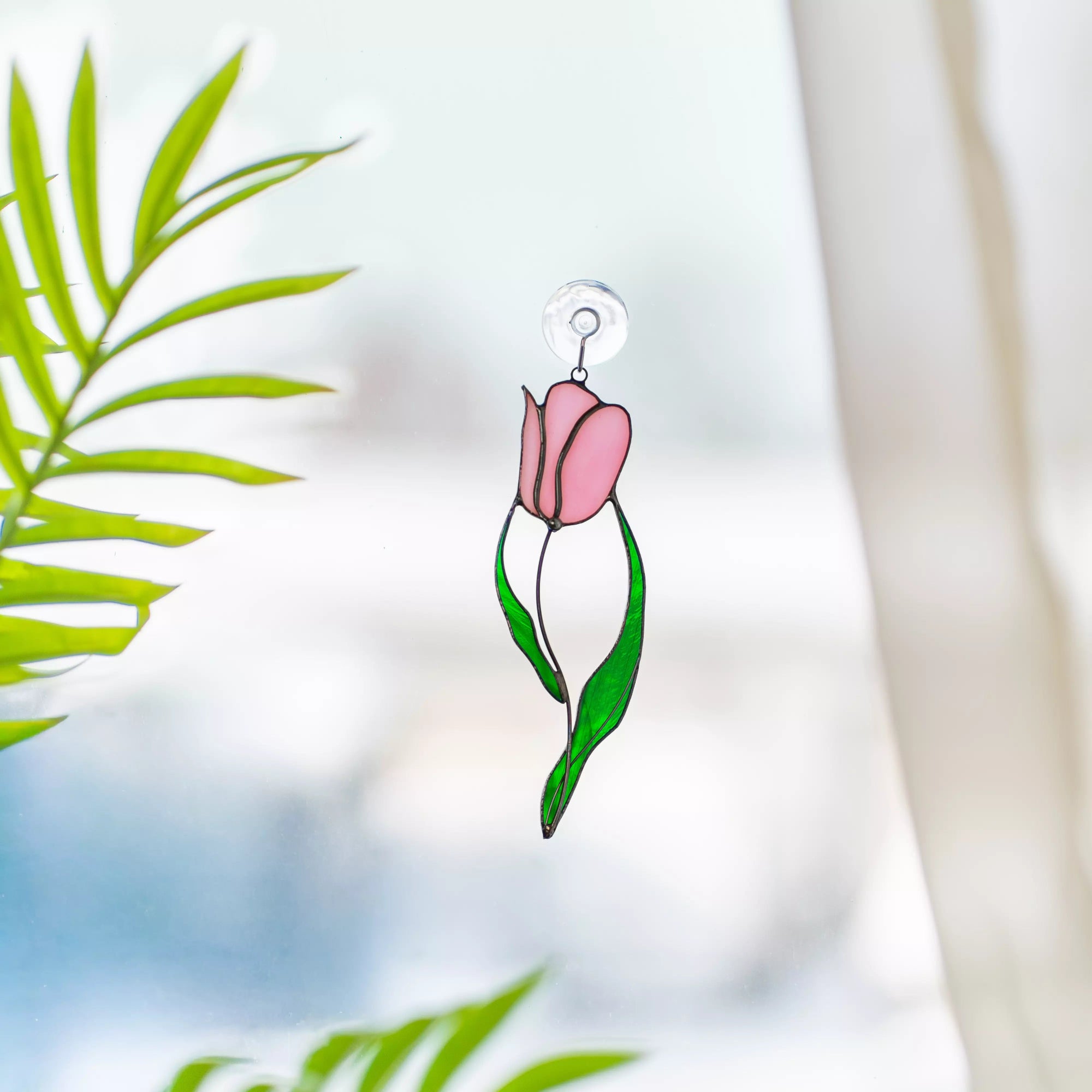 Stained glass suncatcher pink tulip flower hanging against a blurred natural background