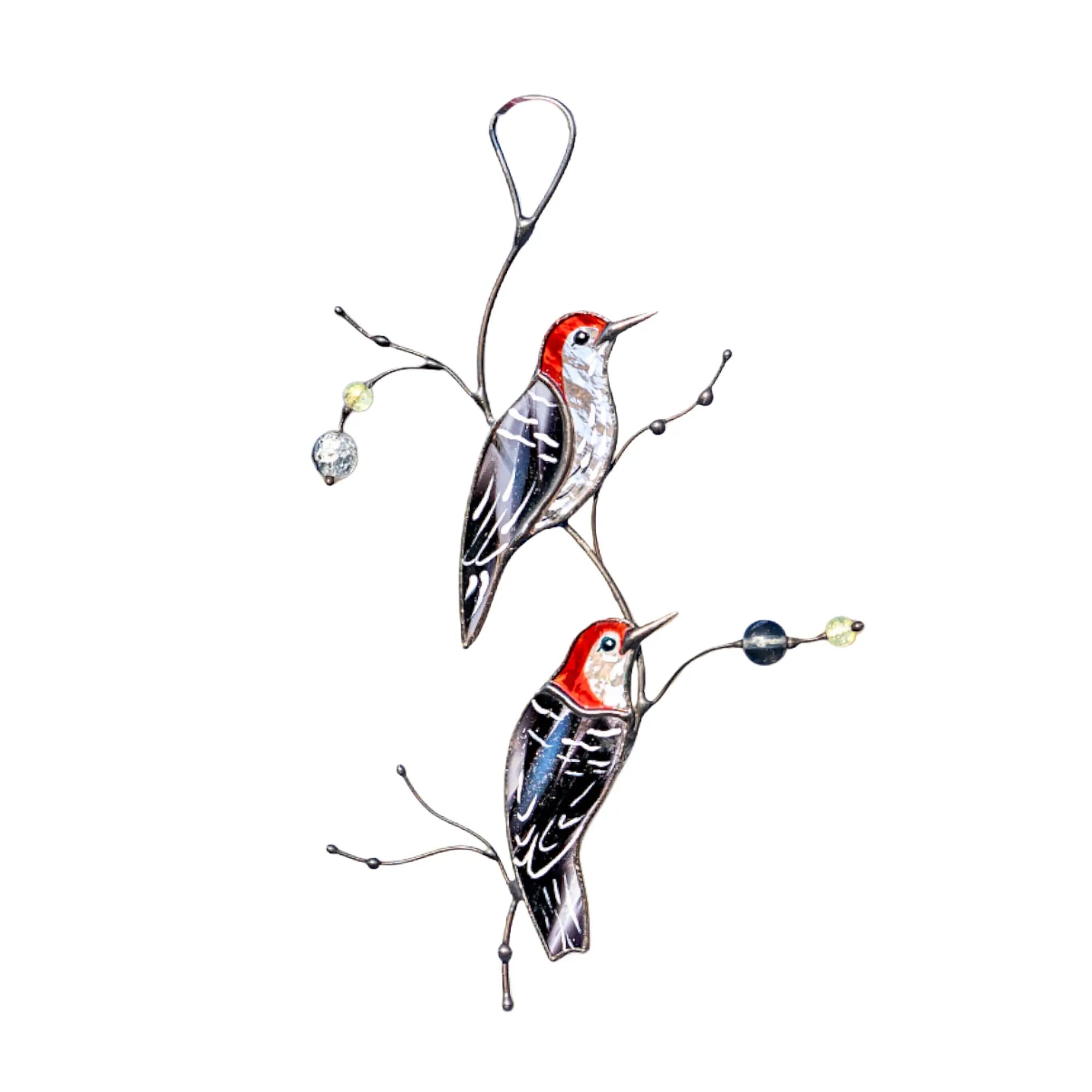 A pair of handcrafted stained glass red-headed woodpeckers with textured black and white wings perched on artistic metal branches, shown against a white background.