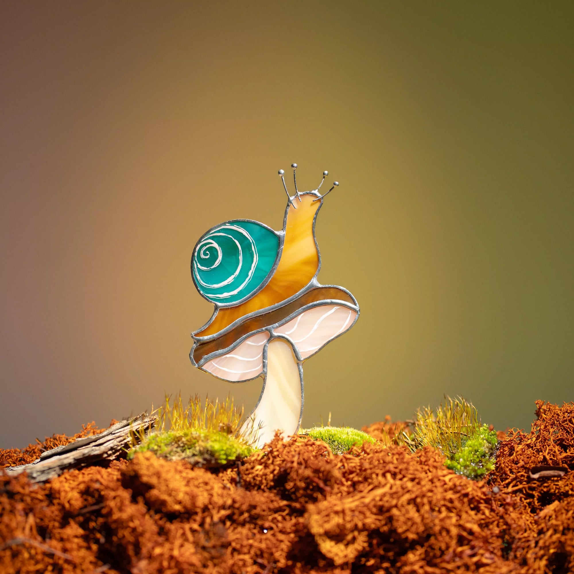 Stained glass snail plant stake on a mushroom with a natural background