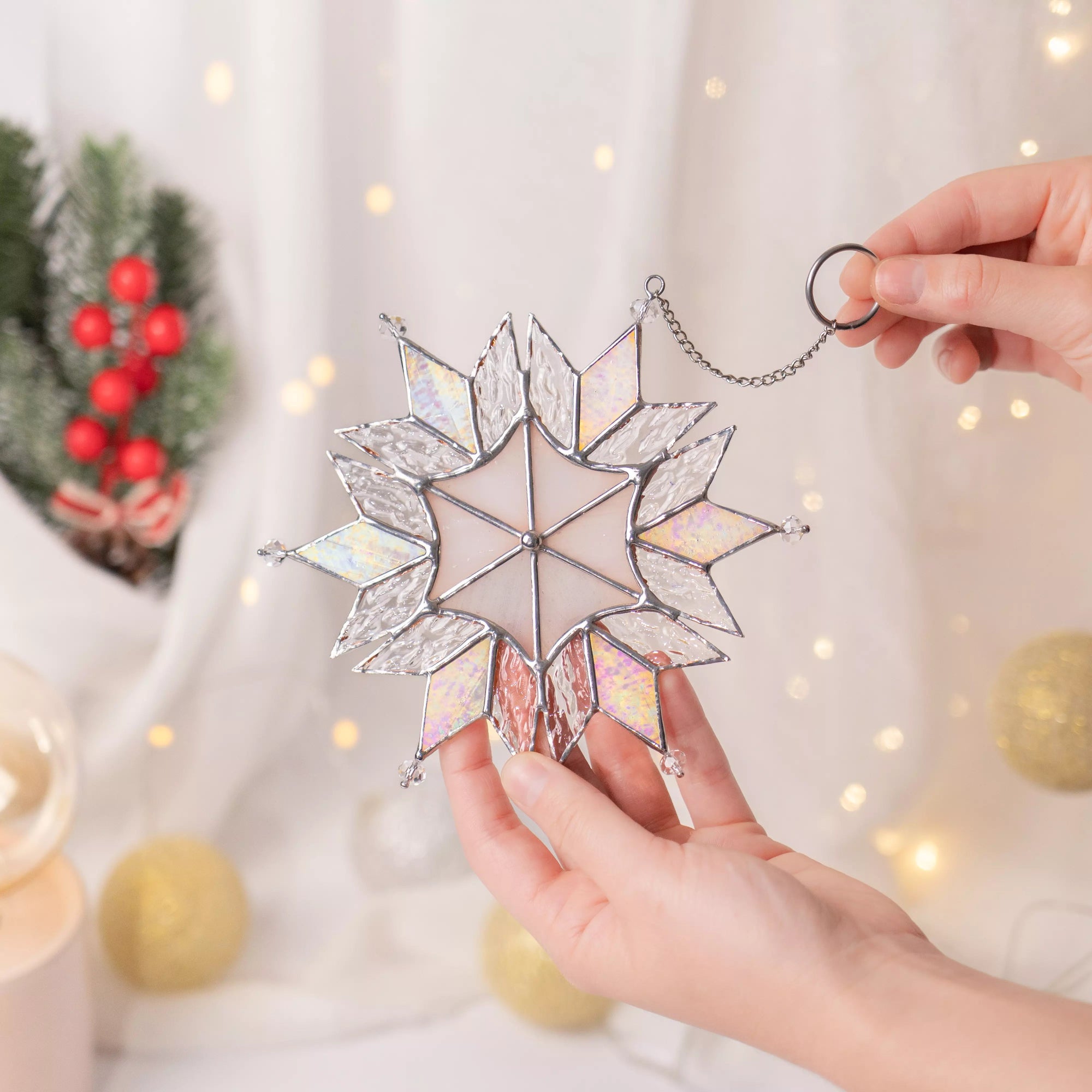 Stained glass suncatcher snowflake Christmas ornament held by hands with festive background