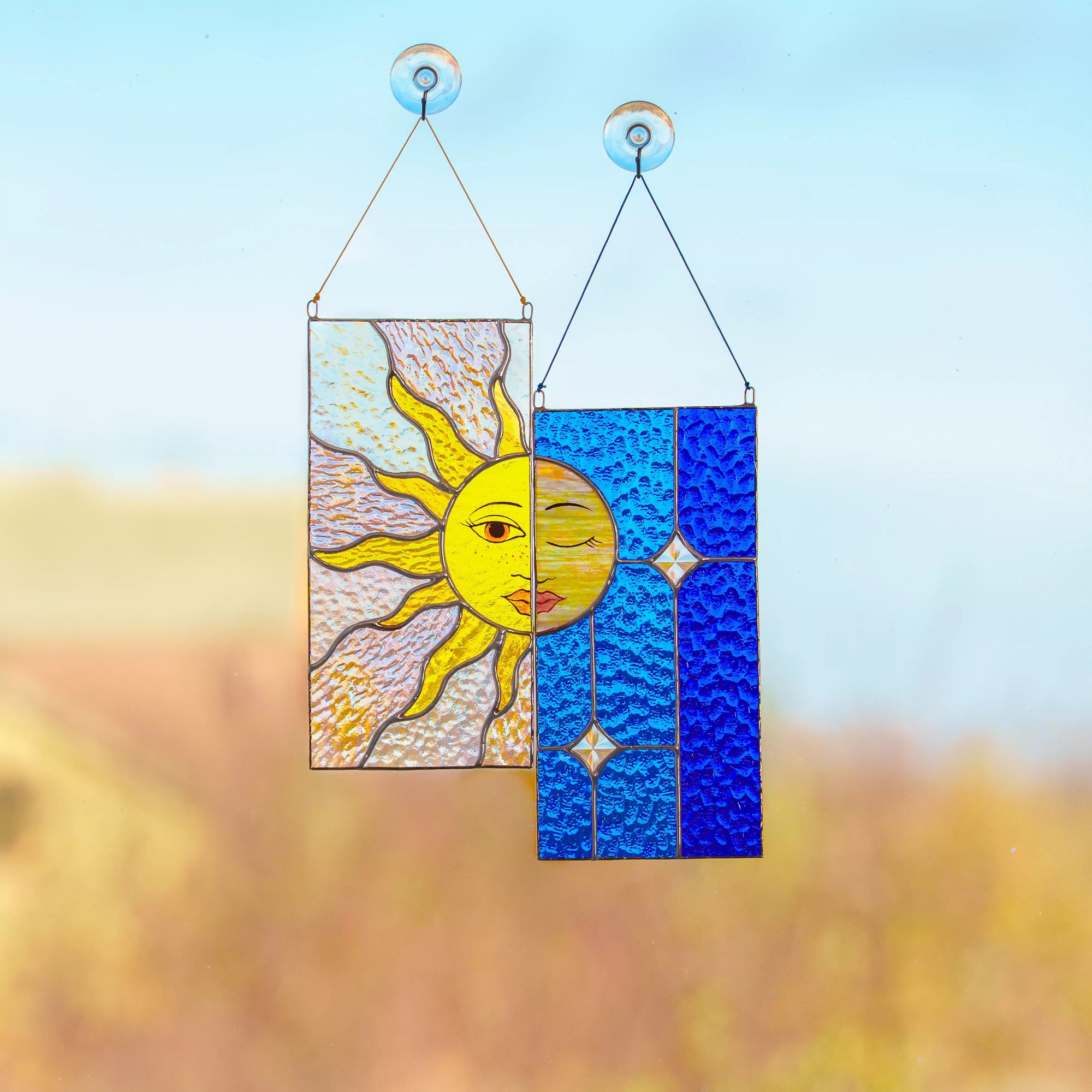 Stained glass sun and moon design hanging against a blurred natural background