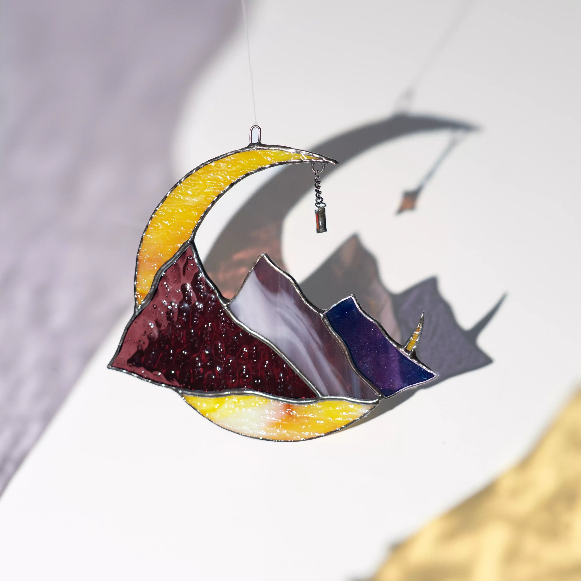 Stained glass celestial suncatcher with mountain and moon design on a white background